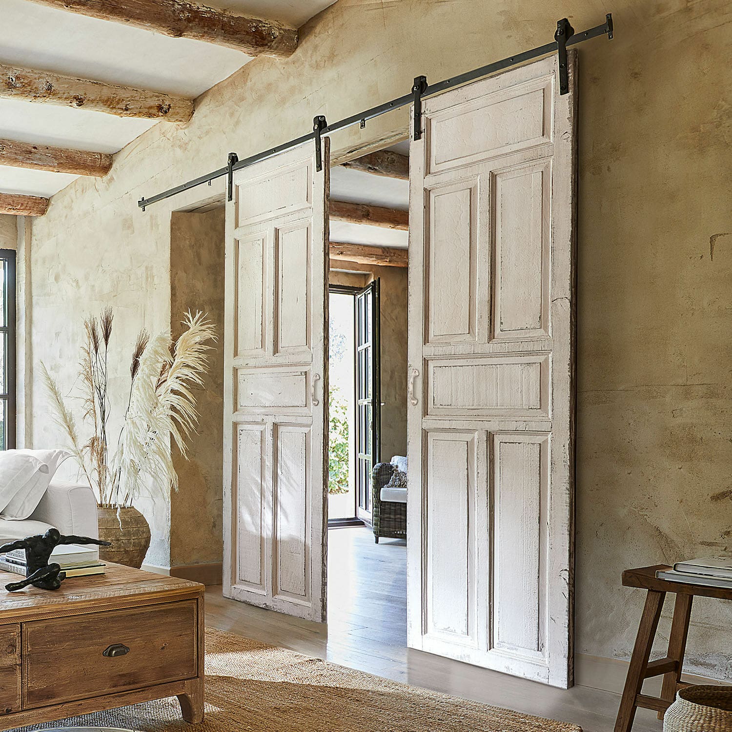 Porta scorrevole a doppia anta Mallothra Porte scorrevoli bianche in legno con sistema metallico in interno rustico con decorazioni naturali