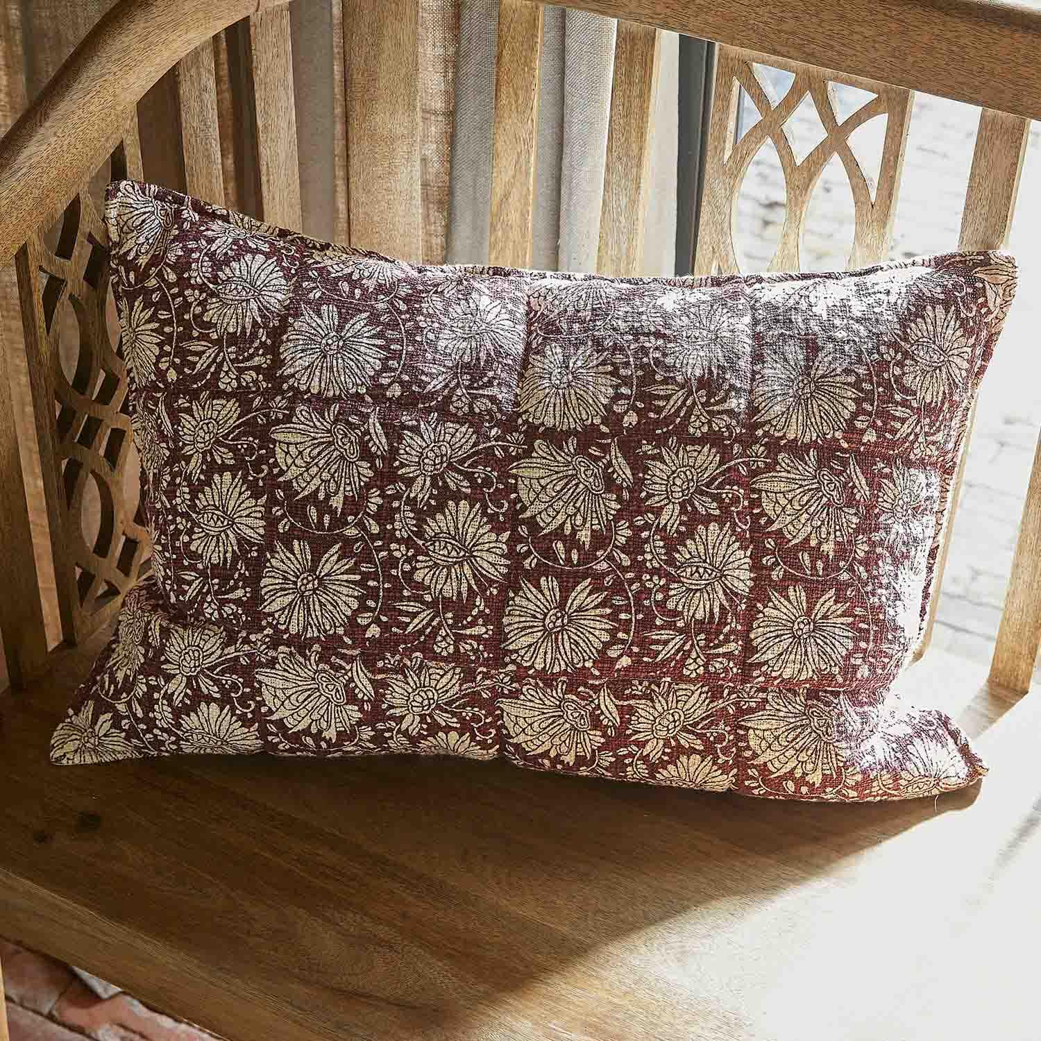 Cuscino decorativo in cotone bordeaux con motivo floreale crema su panca in legno