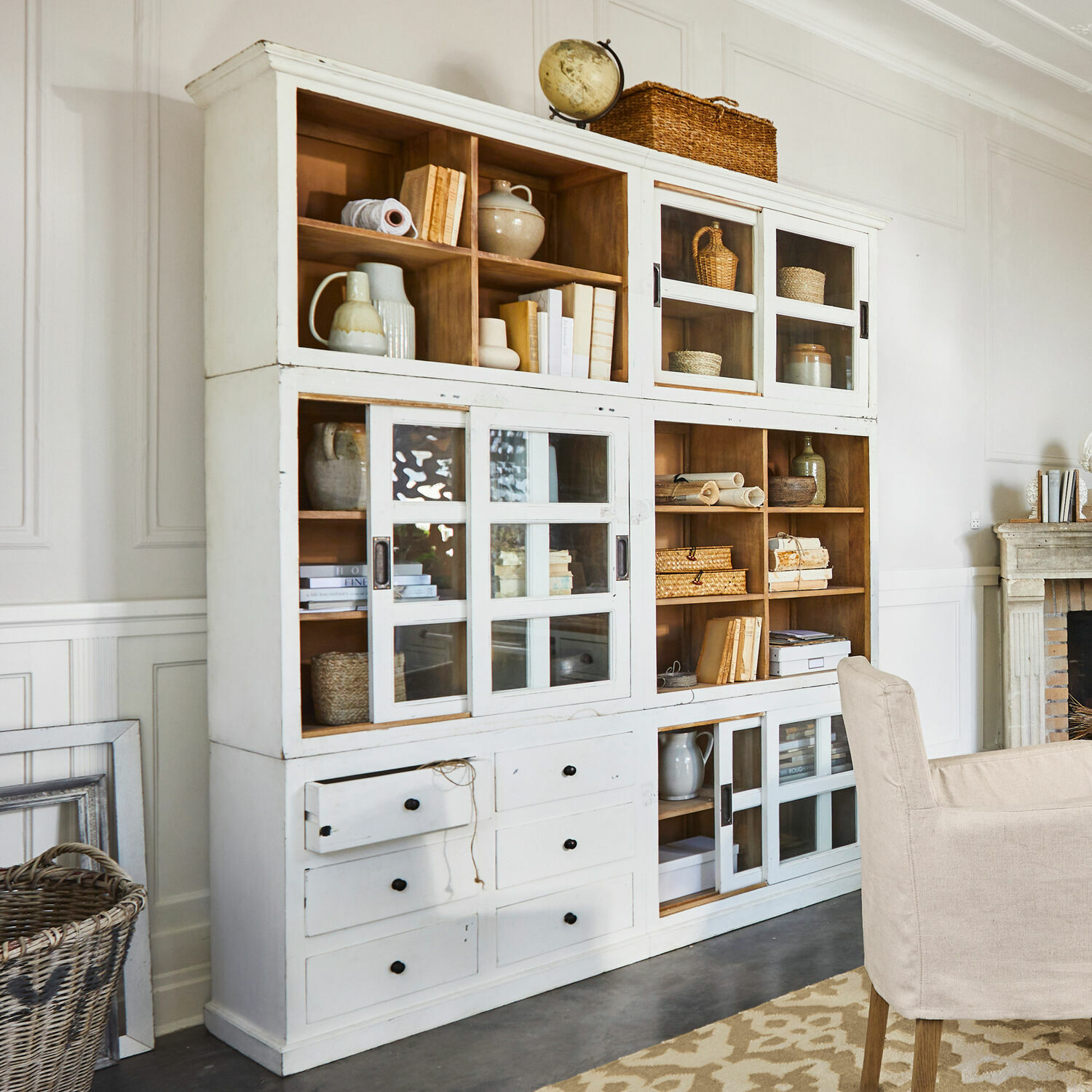 Credenza Dubberly Mobile in legno bianco con ante in vetro e cassetti, stile vintage, decorato con libri e cesti