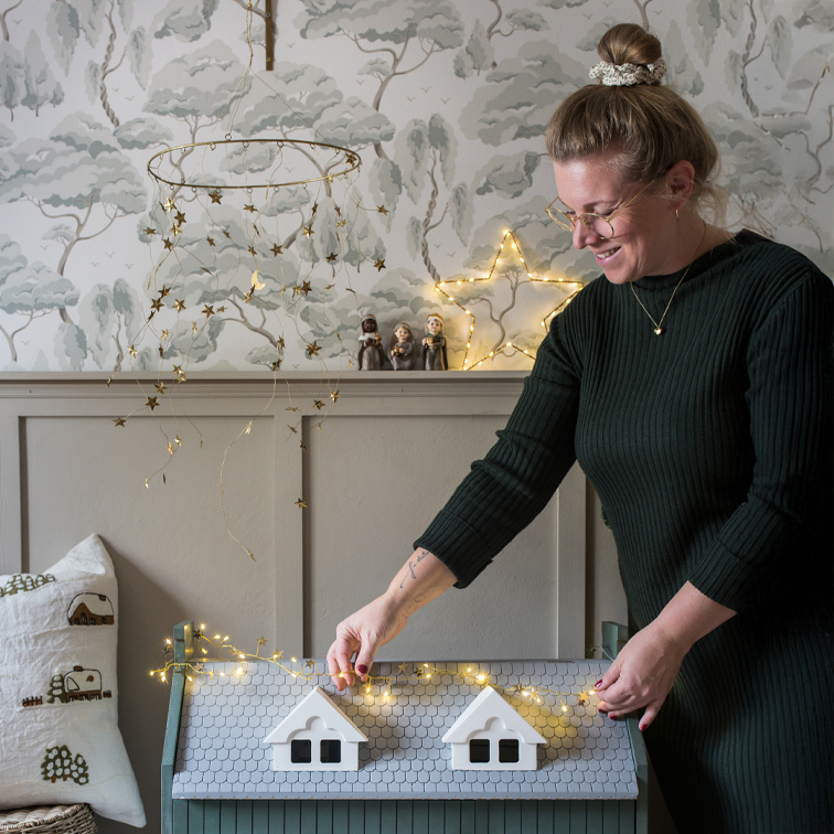 Donna decora un baule di legno grigio con luci a LED a forma di stelle in un ambiente accogliente