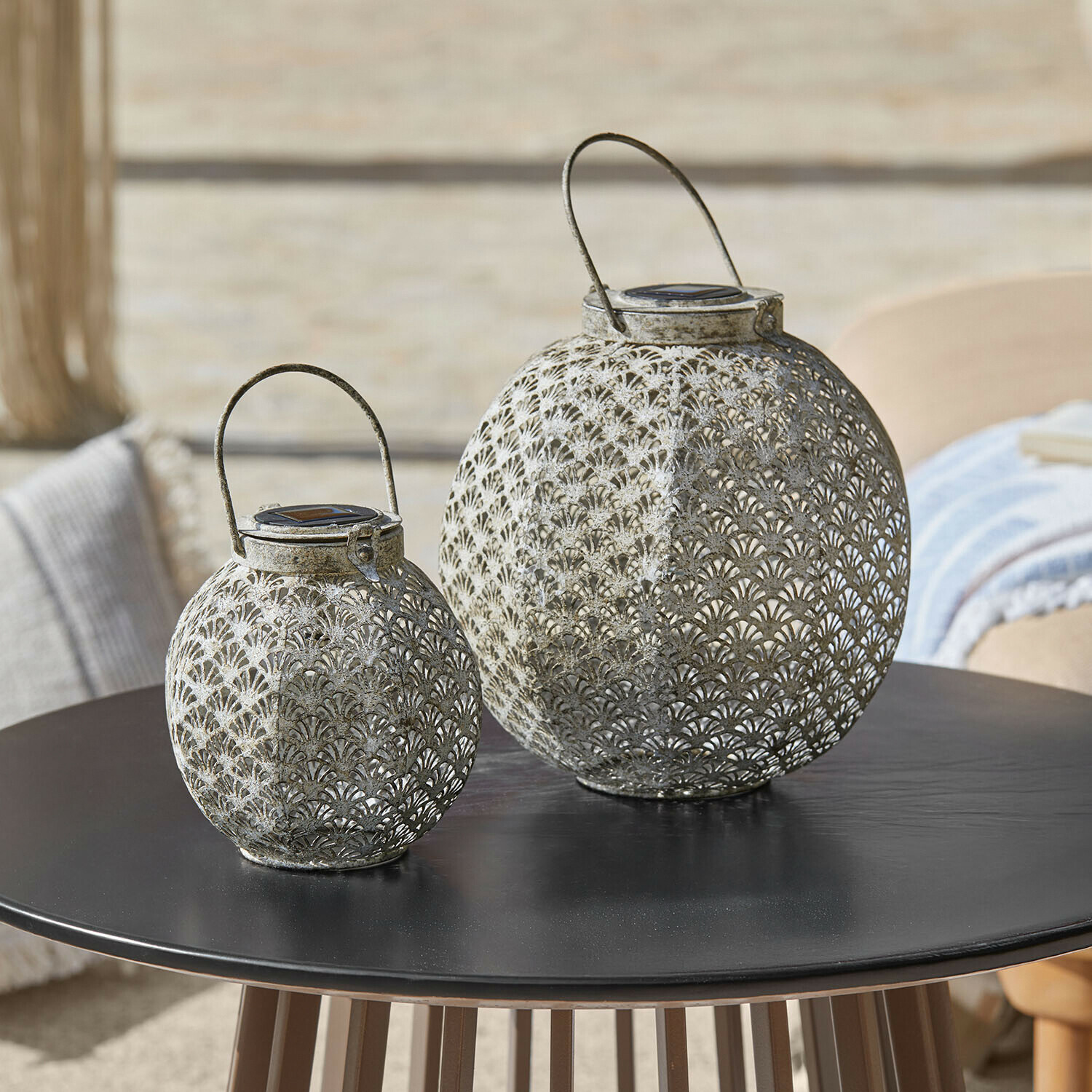 Coppia di lanterne solari Omirah Due lanterne in metallo traforato grigio su tavolo nero, decorazione elegante per esterni