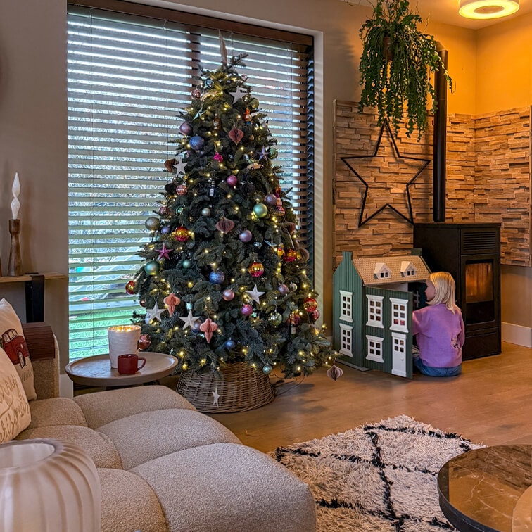 Soggiorno accogliente con albero di Natale decorato, divano morbido e bambino che gioca con casa delle bambole