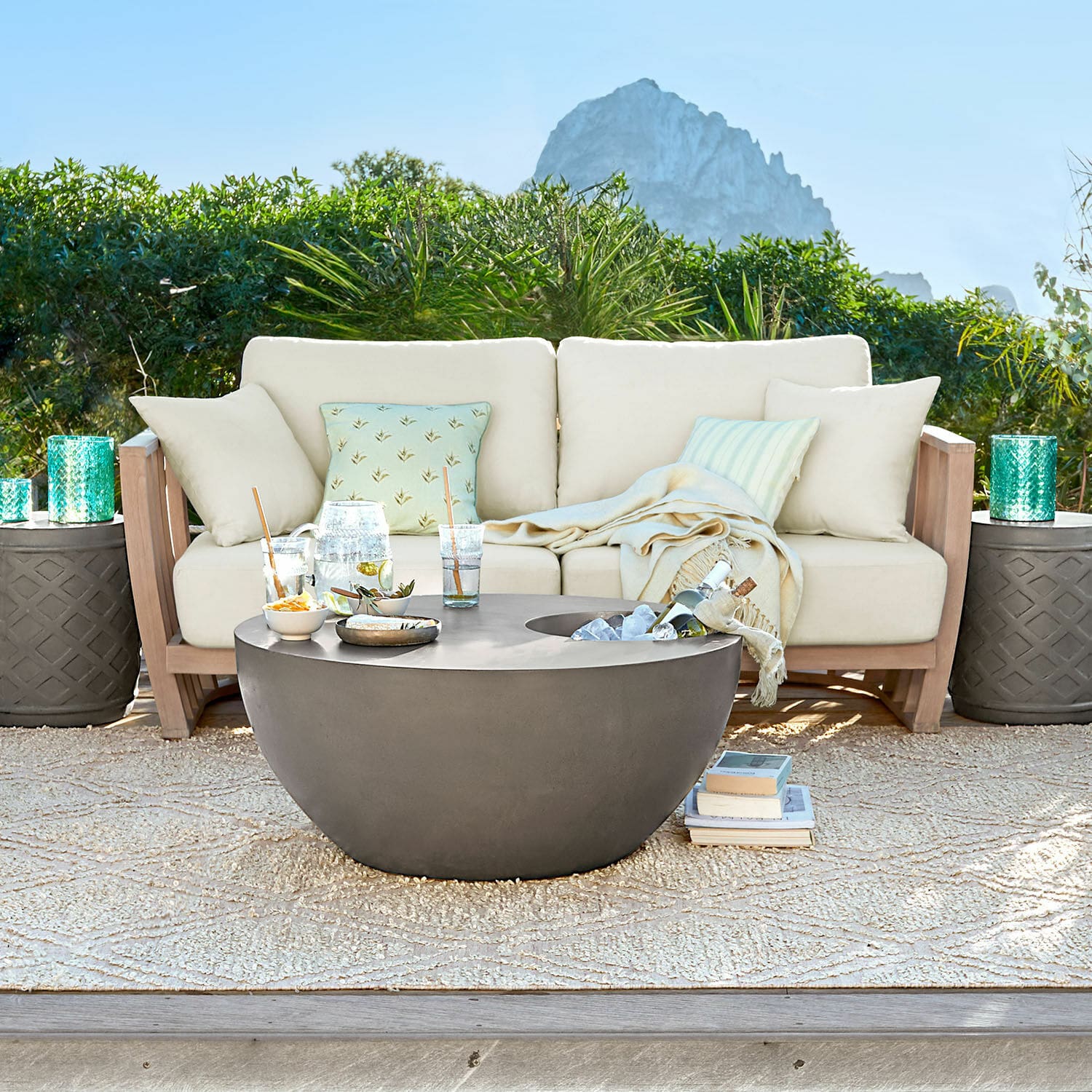 Divano FSC®-100% Vézère Tavolino da giardino rotondo moderno in cemento grigio su terrazza con divano beige e cuscini
