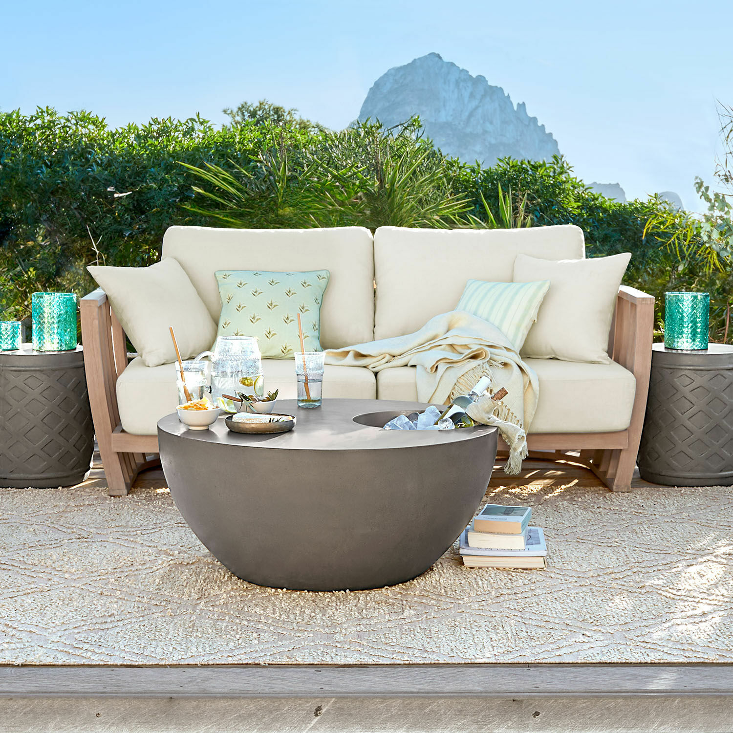 Divano FSC®-100% Vézère Tavolino da giardino rotondo moderno in cemento grigio su terrazza con divano beige e cuscini