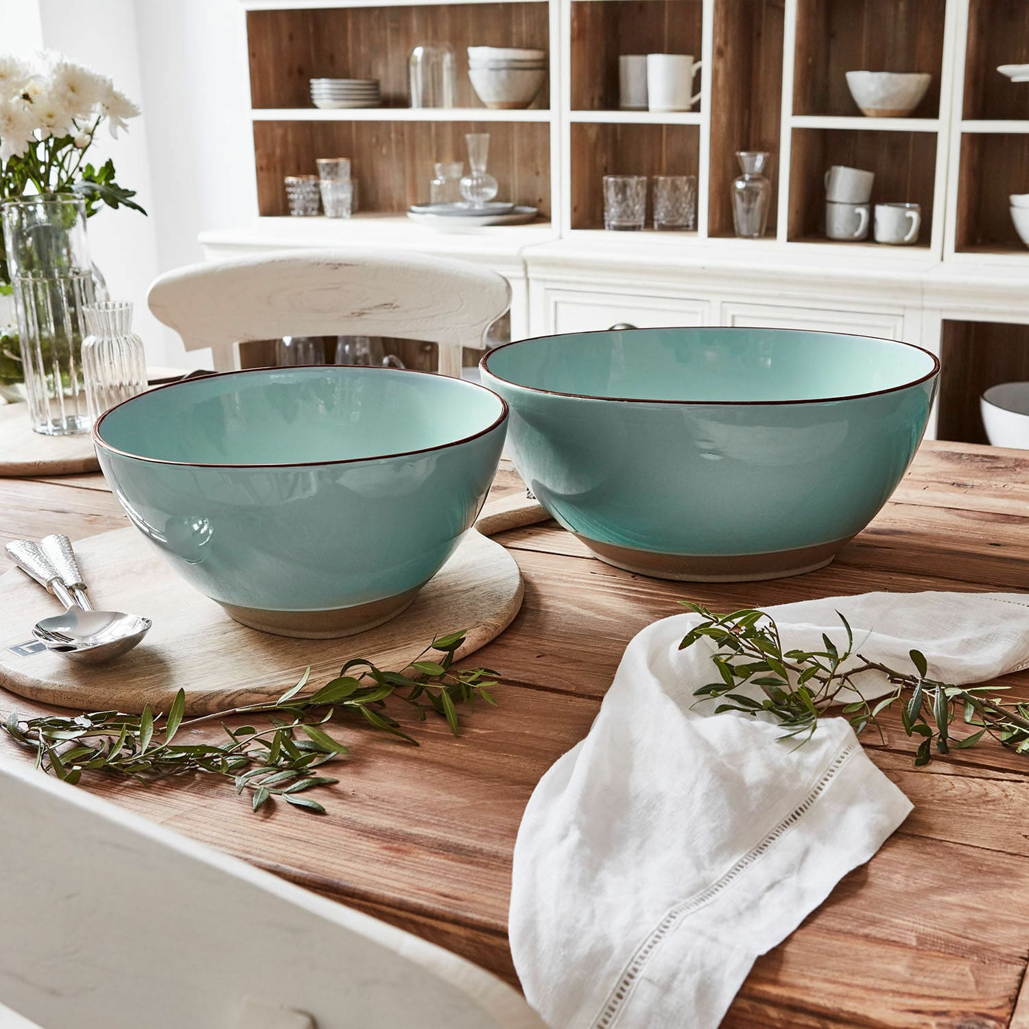 Coppia di insalatiere Biarré Set di due ciotole in ceramica turchese su tavolo in legno con decorazione di rami verdi