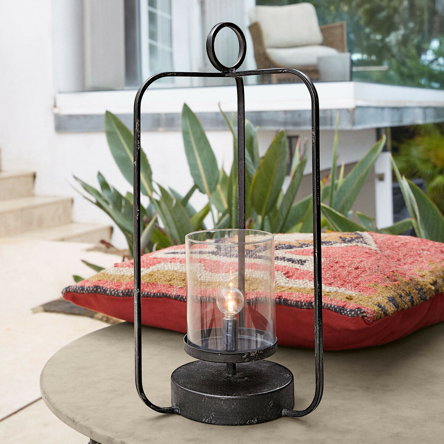 Lanterna a LED Kivalex Lanterna nera in metallo con vetro trasparente su tavolo da giardino con cuscino colorato