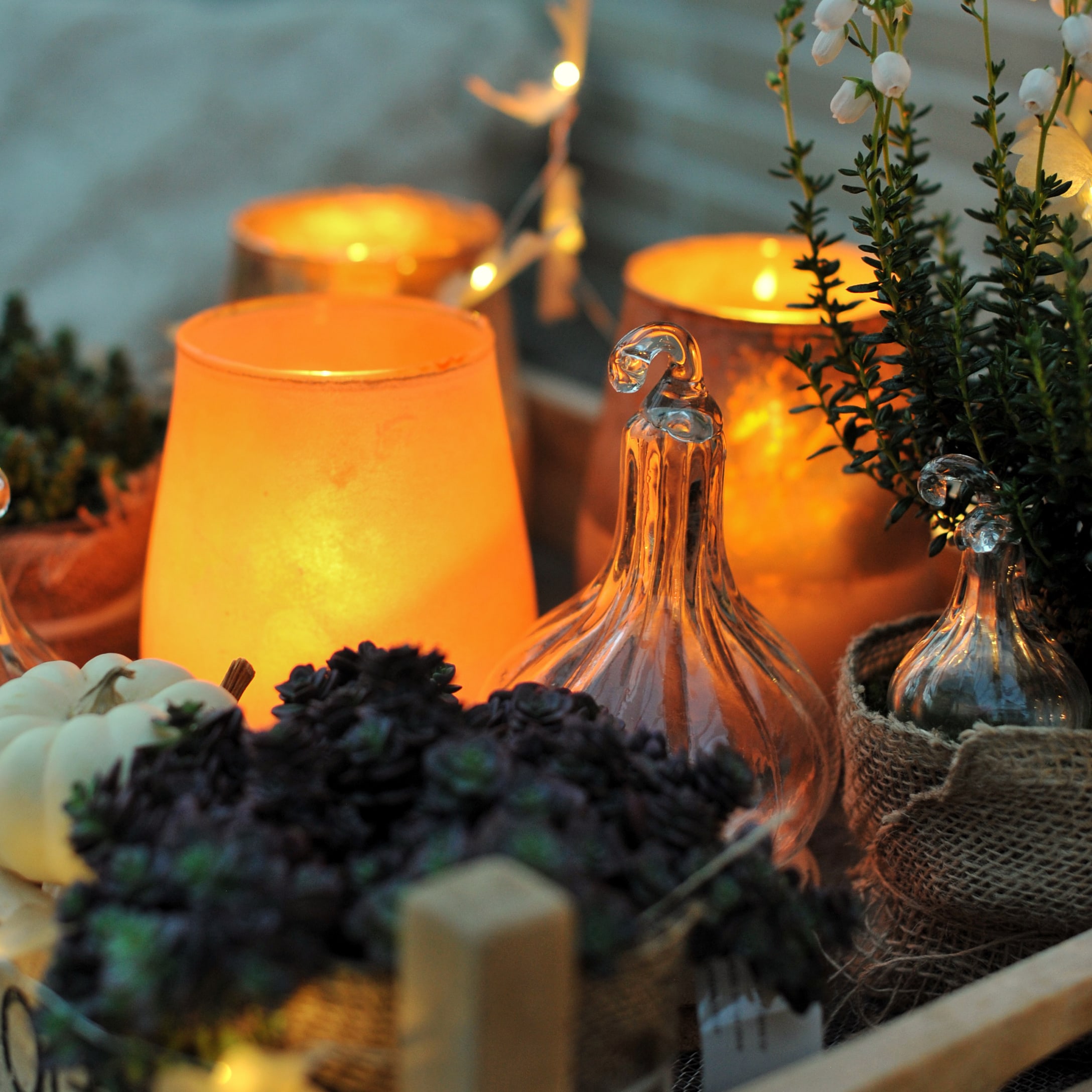 Decorazione autunnale con zucche di vetro e candele arancioni per un'atmosfera accogliente