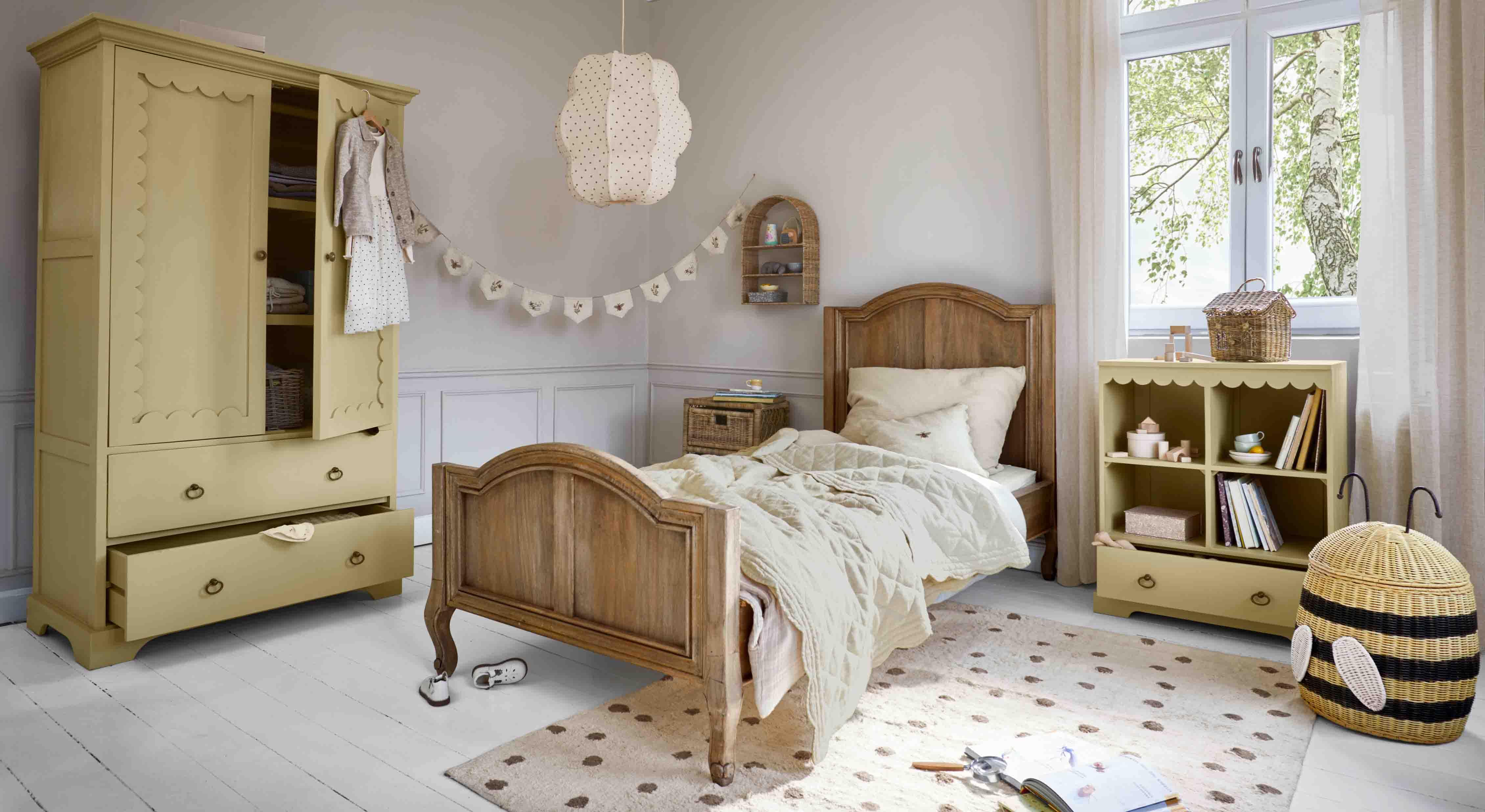 Camera per bambini accogliente con letto in legno, armadio giallo e scaffale in legno e vimini