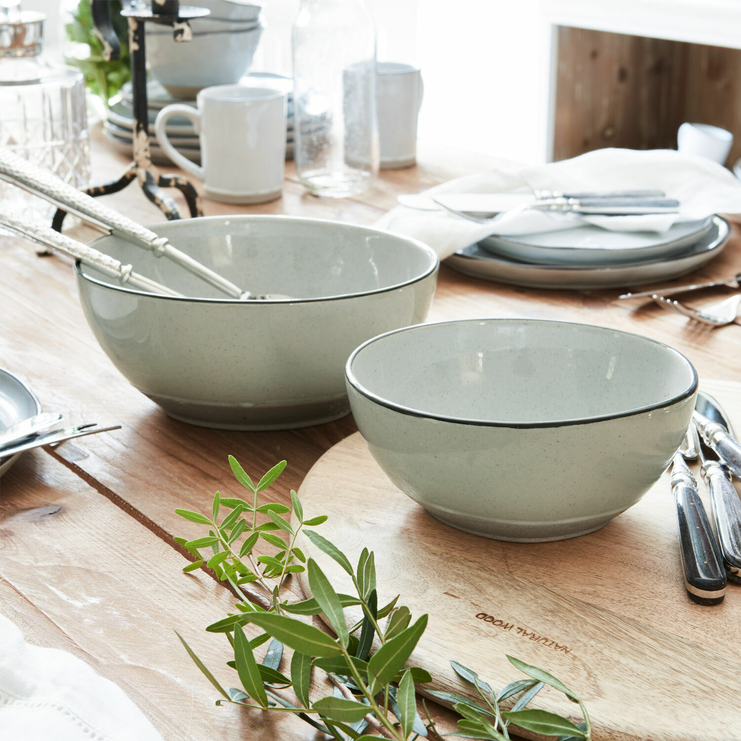 Coppia di ciotole Biarré Set di ciotole in ceramica grigio chiaro su tavolo in legno con decorazione di foglie verdi