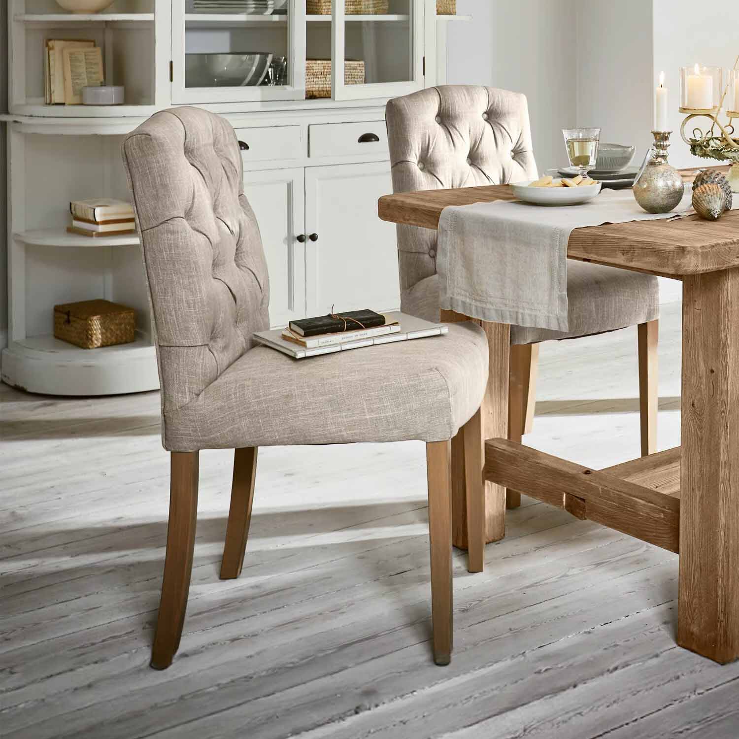 Sedia imbottita beige con gambe in legno accanto a tavolo in legno in sala da pranzo luminosa