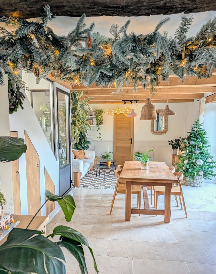 Interno accogliente con tavolo in legno, albero di Natale e luci decorative in colori naturali