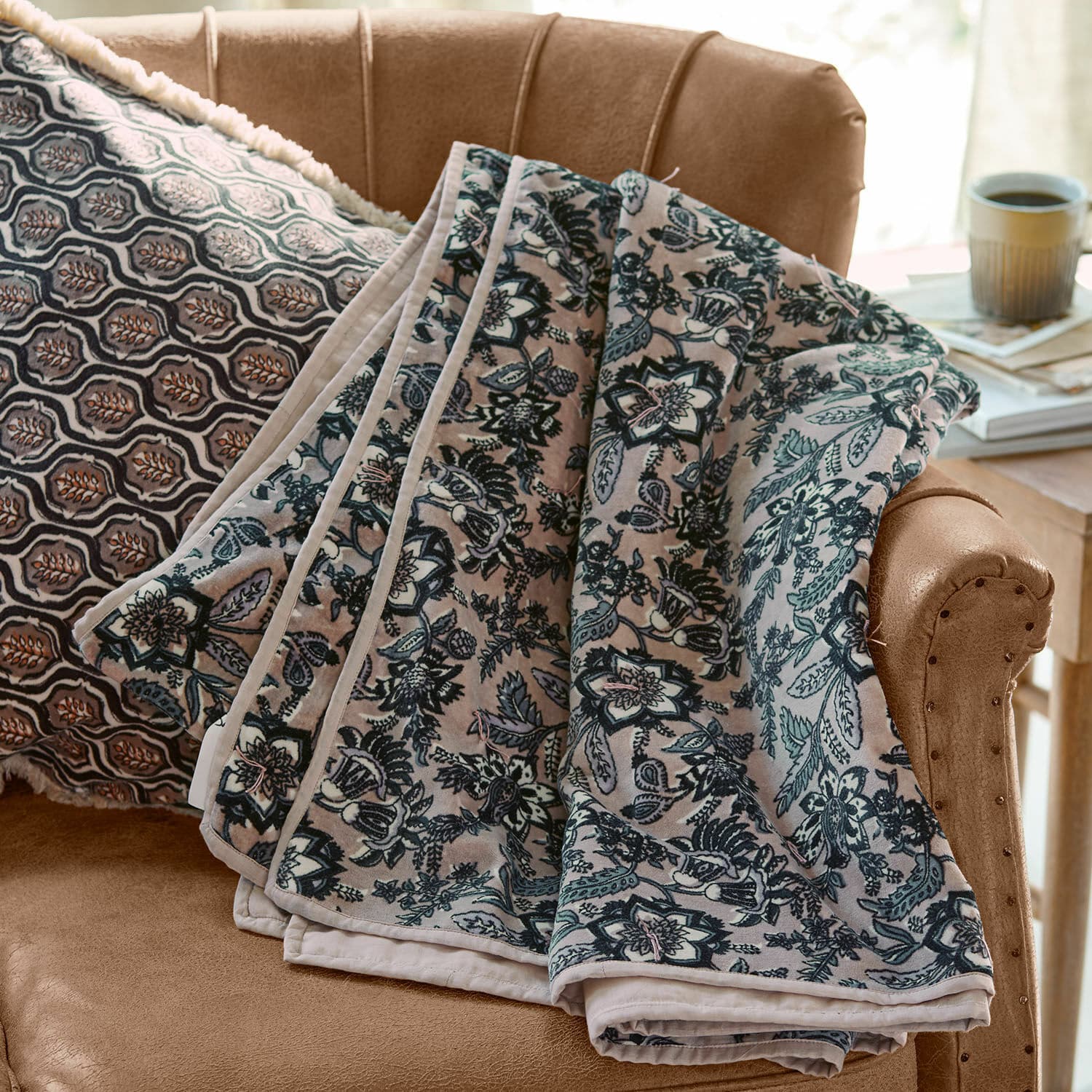 Plaid Elarion Coperta morbida con motivo floreale grigio su divano beige con cuscino decorativo