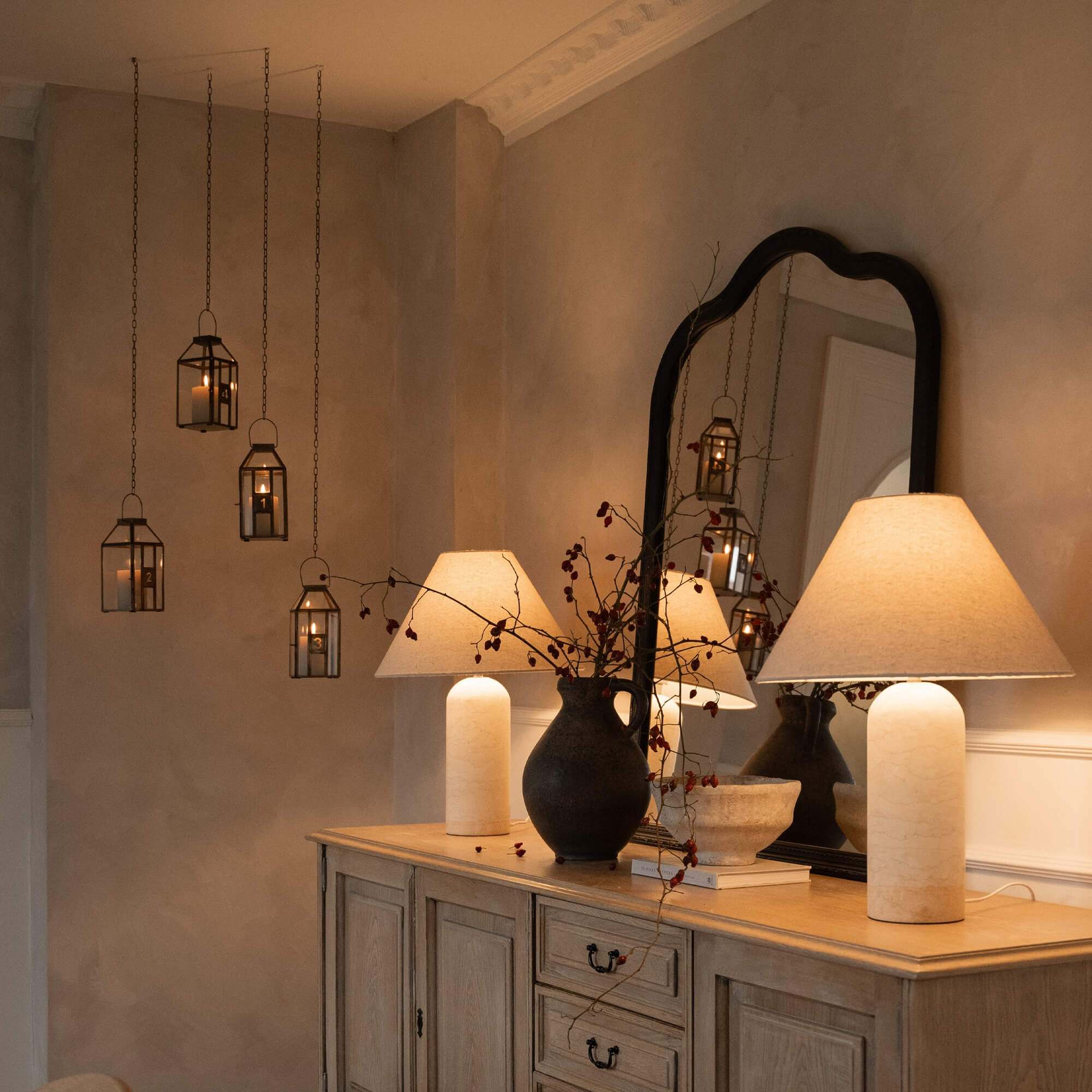 Corona d'Avvento decorativa con lanterne in metallo e candele in un ambiente accogliente