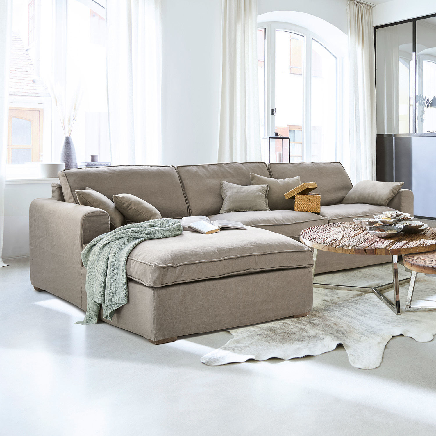 Divano Seaford Divano angolare beige in tessuto in soggiorno luminoso con tavolino in legno e decorazioni