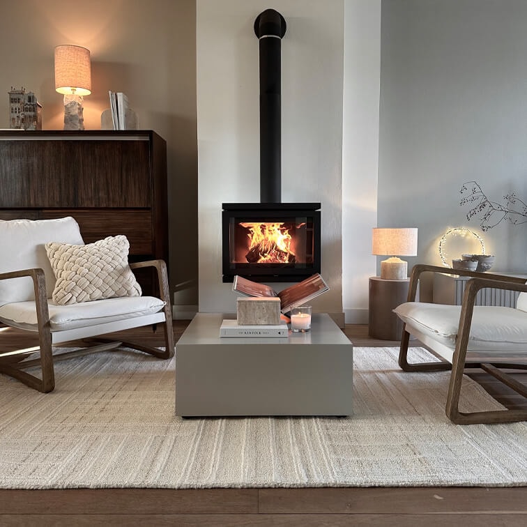 Soggiorno moderno con camino a legna, tappeto beige e due poltrone in legno con cuscini bianchi