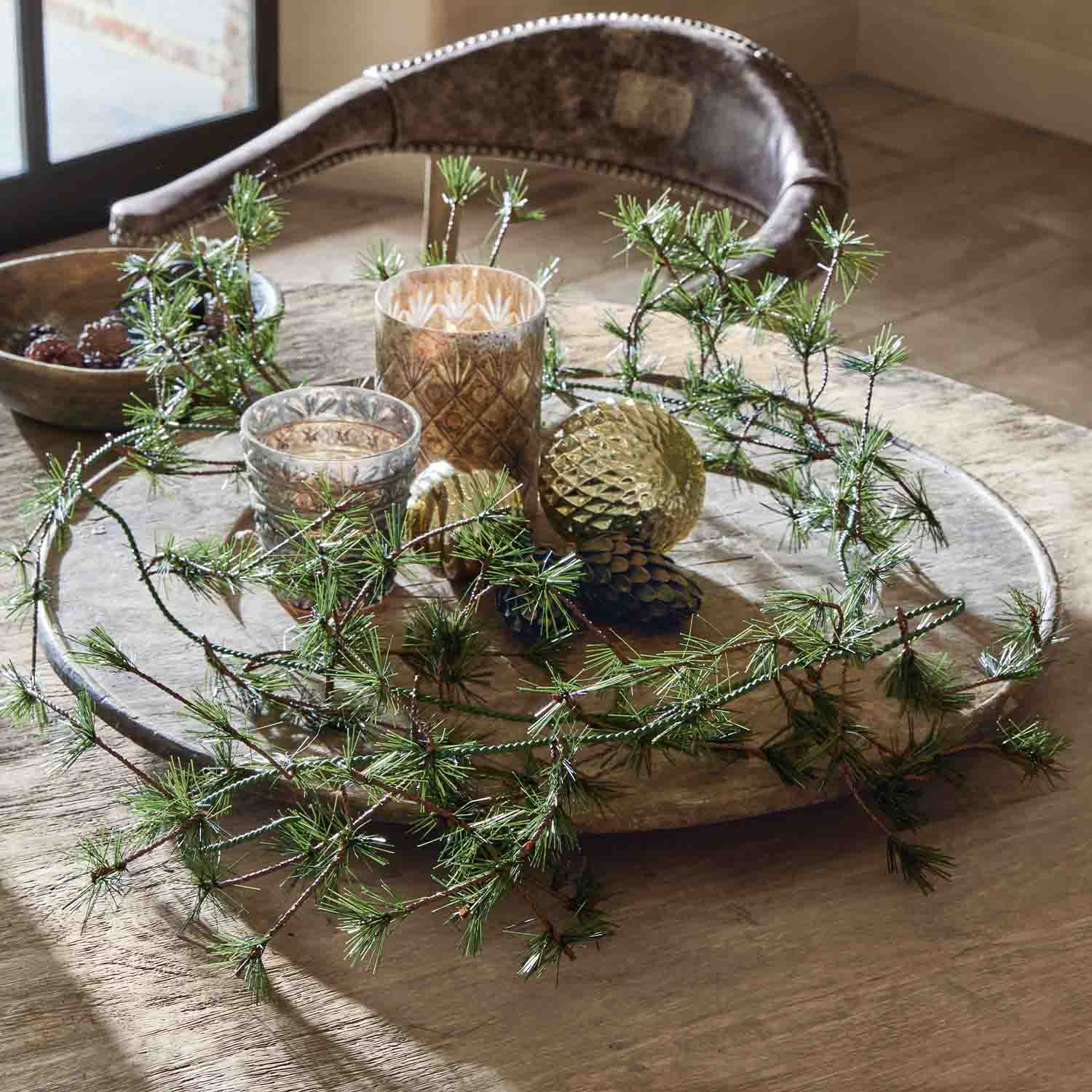 Vassoio in legno decorativo con rami verdi, ornamenti dorati e portacandele in vetro su tavolo