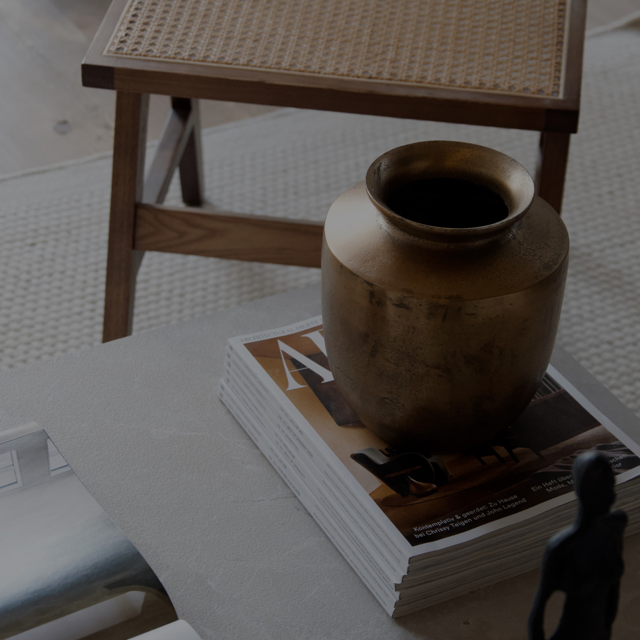 Vaso decorativo in ottone su pila di riviste su tavolo grigio in interno moderno