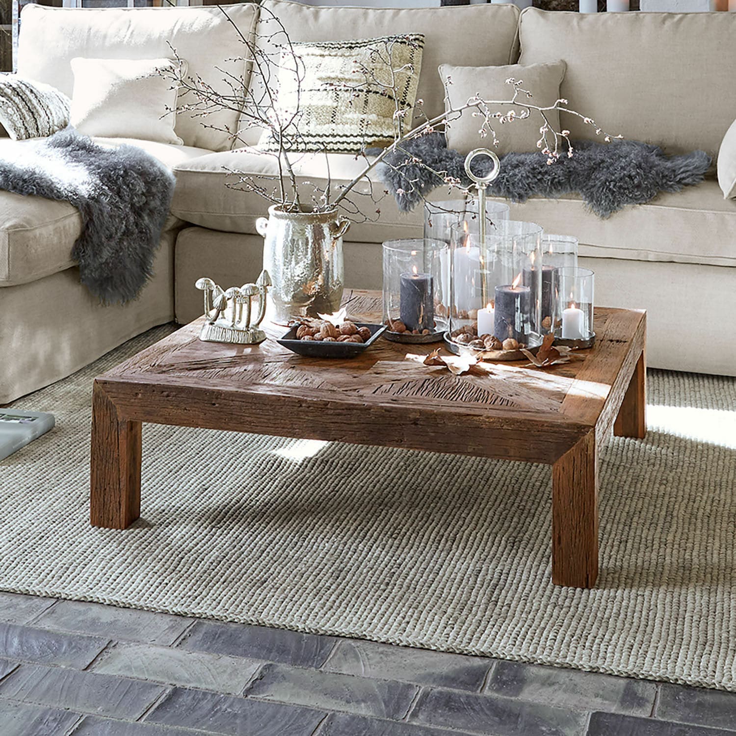 Tavolino da salotto Vivacetto Tavolino quadrato in legno con candele decorative e elementi naturali su tappeto beige in soggiorno