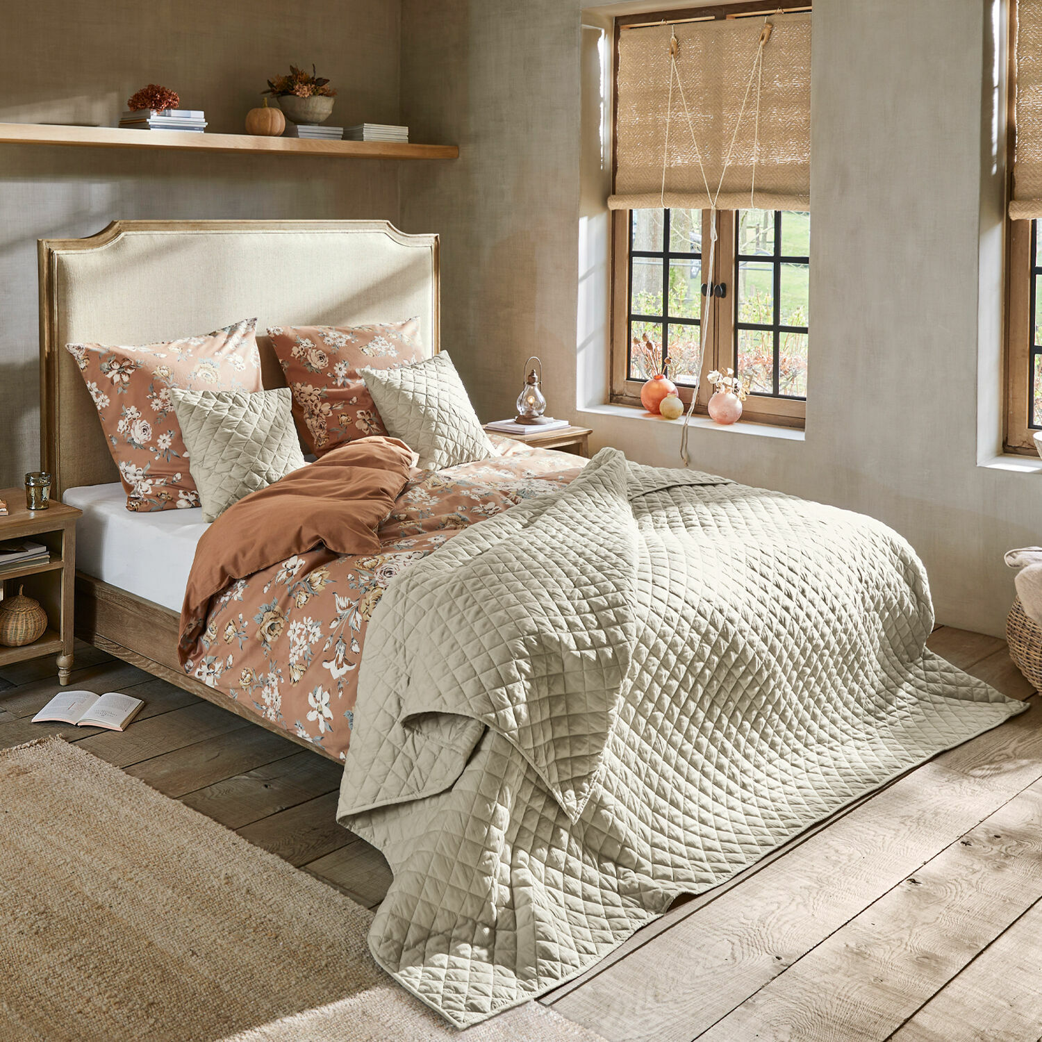 Letto Catham Camera accogliente con letto coperto da trapunta beige trapuntata e biancheria da letto floreale dai toni caldi