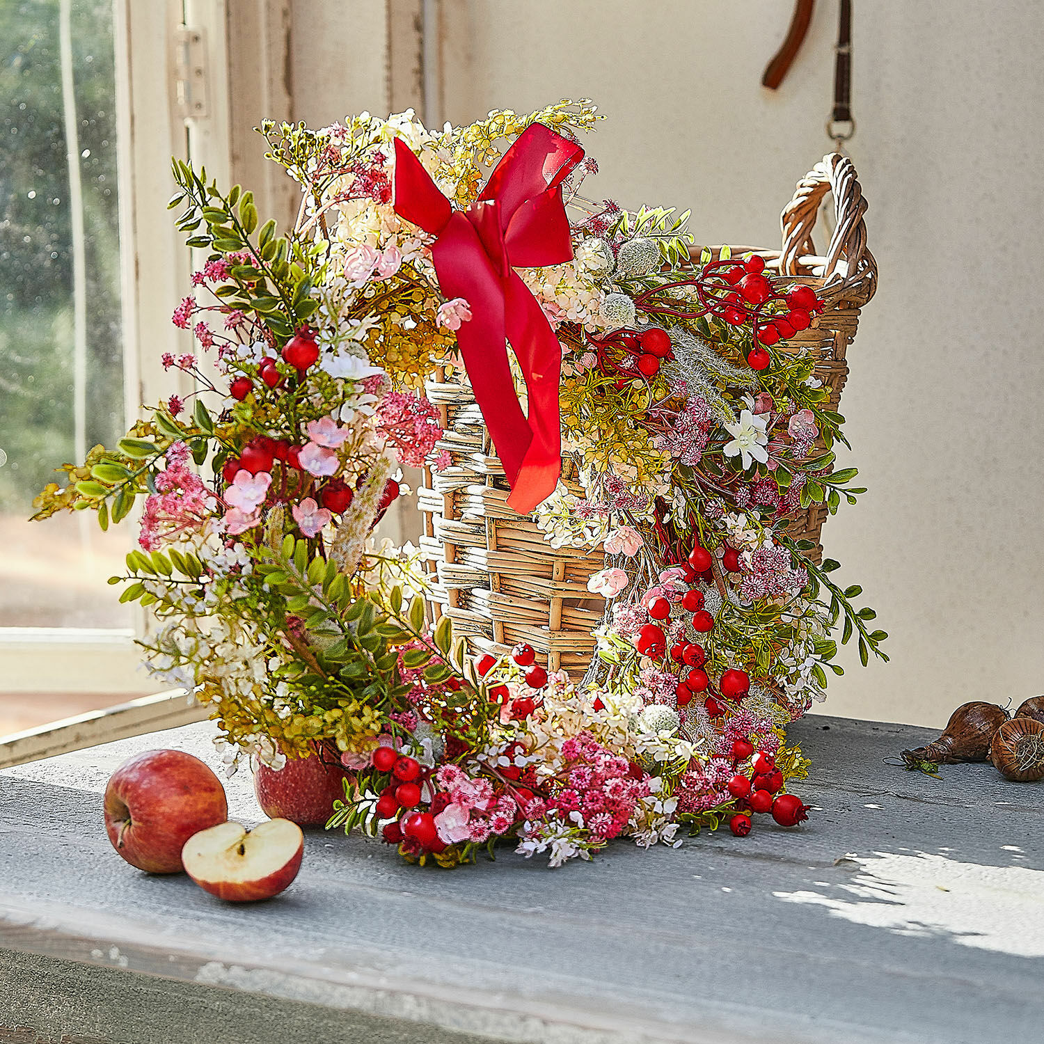 Ghirlanda Selivane Corona decorativa con bacche rosse e fiori rosa su cesta di vimini su tavolo