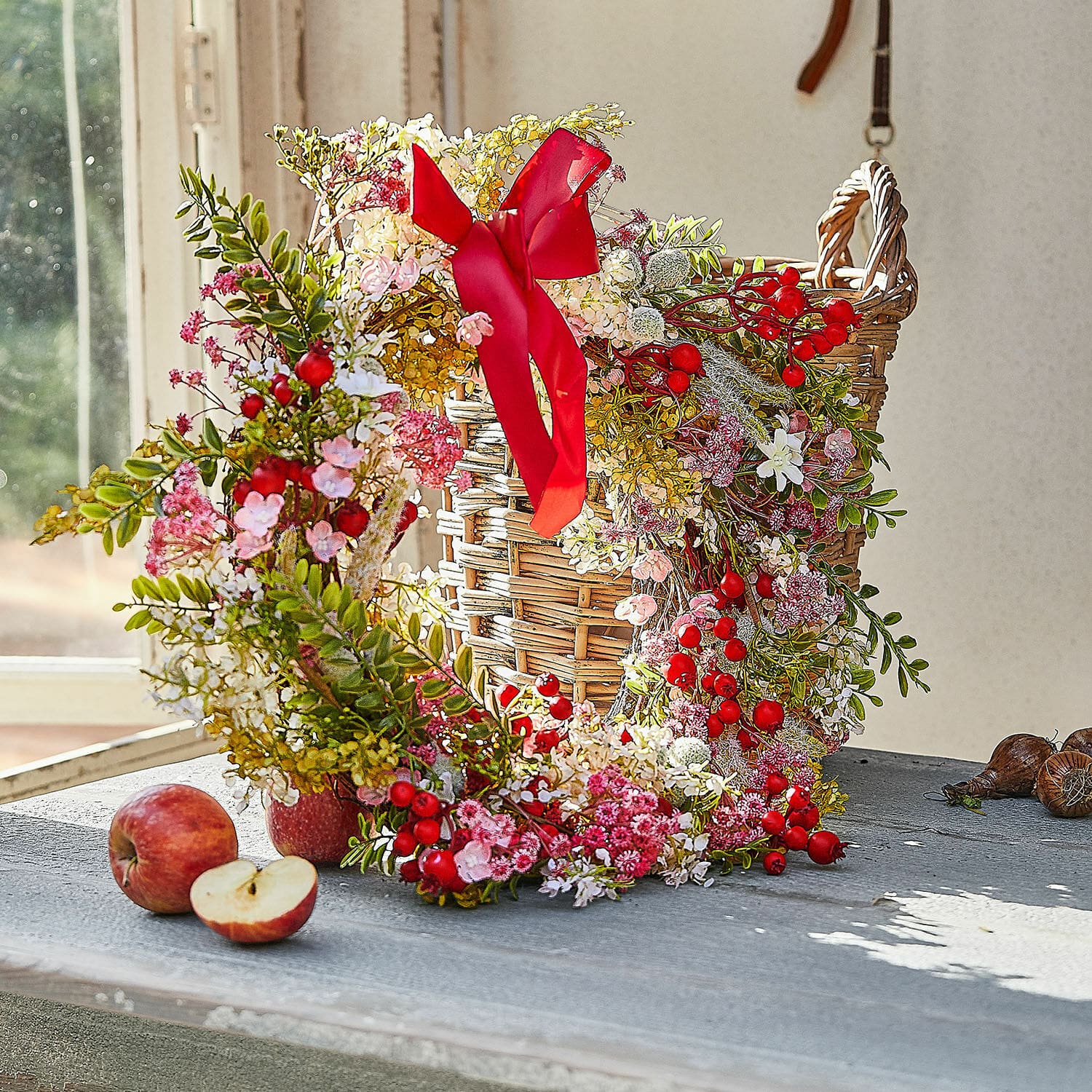 Ghirlanda Selivane Corona decorativa con bacche rosse e fiori rosa su cesta di vimini su tavolo