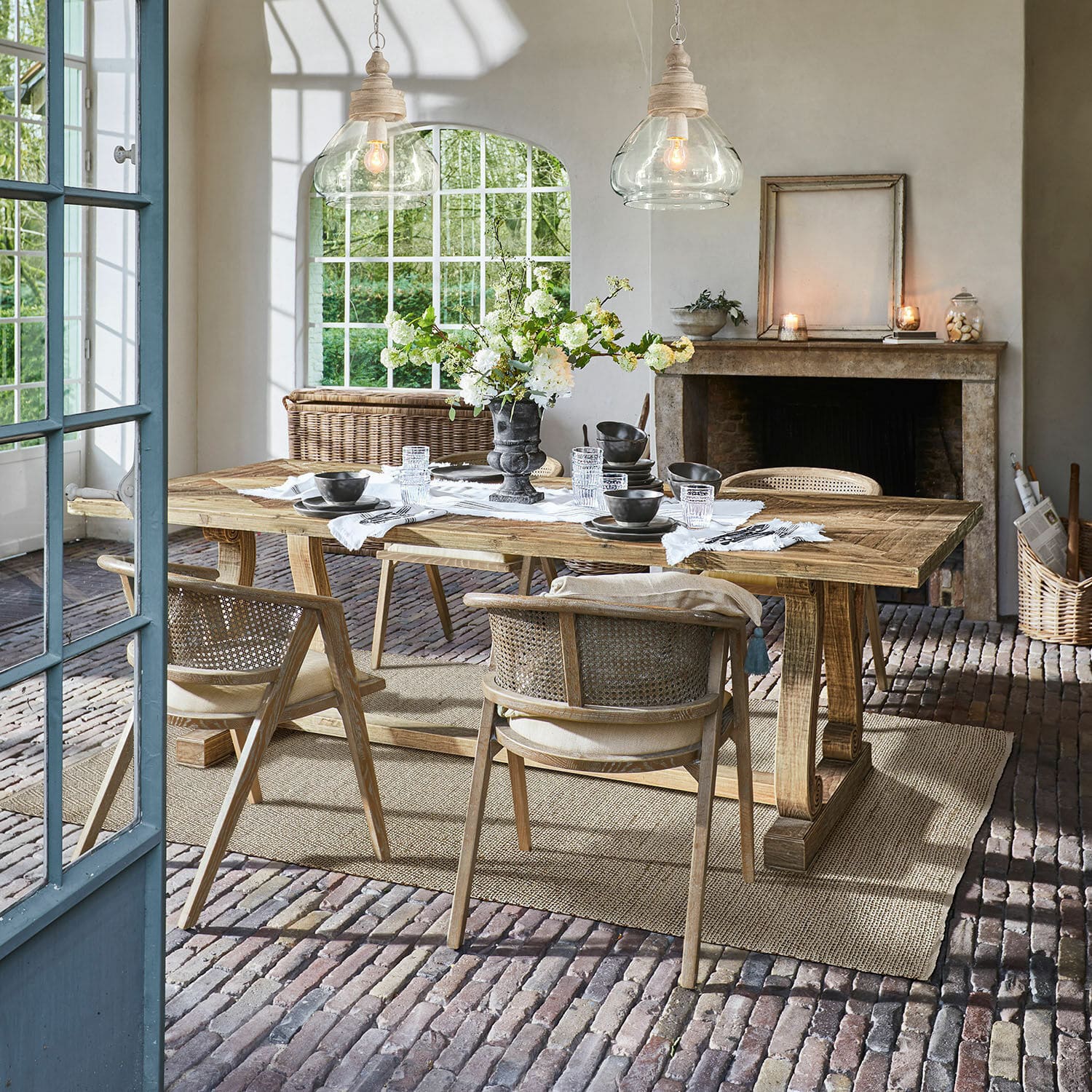 Tavolo Campbelltown Sala da pranzo con tavolo in legno e sedie in vimini su pavimento in mattoni con decorazioni floreali