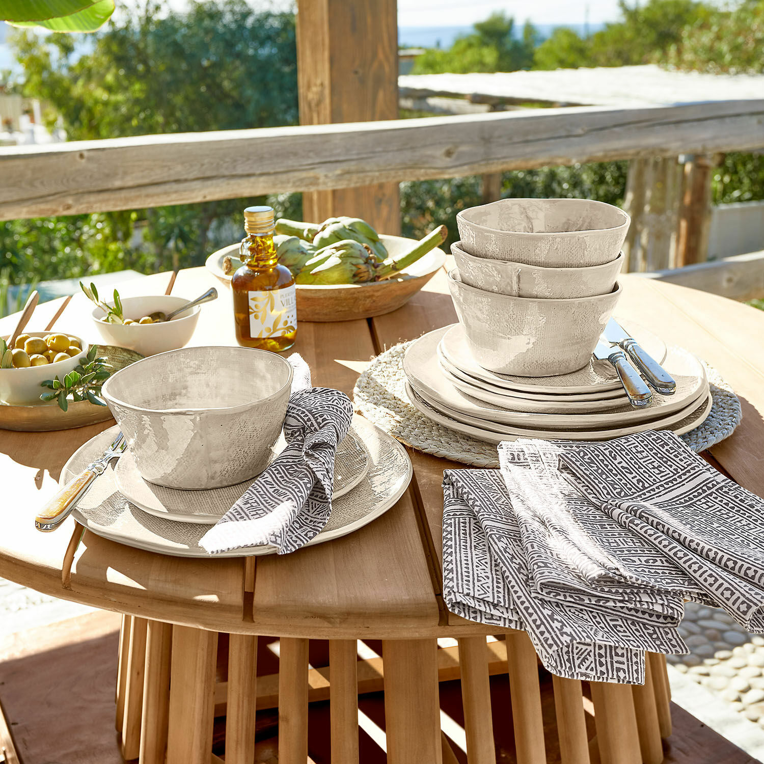 Servizio di 12 stoviglie Luganville Set di stoviglie in ceramica beige con ciotole e piatti su tavolo in legno all'aperto