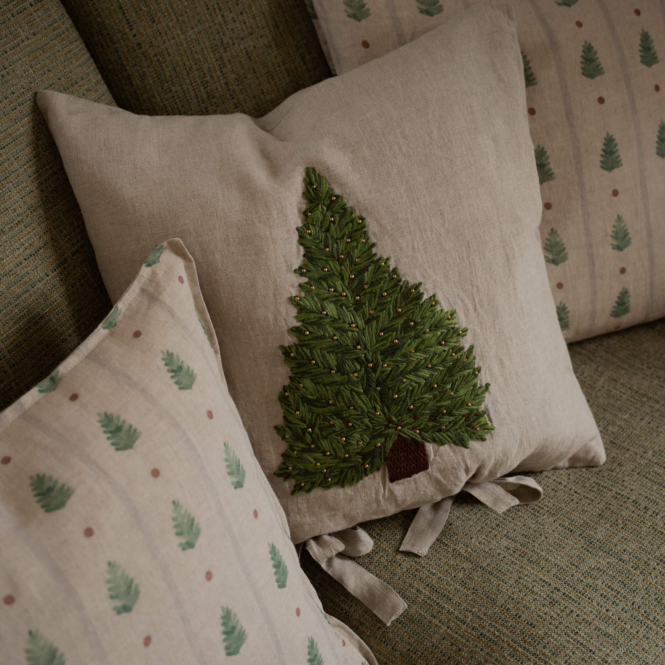 Cuscino in lino beige con albero verde ricamato e perline decorative su divano