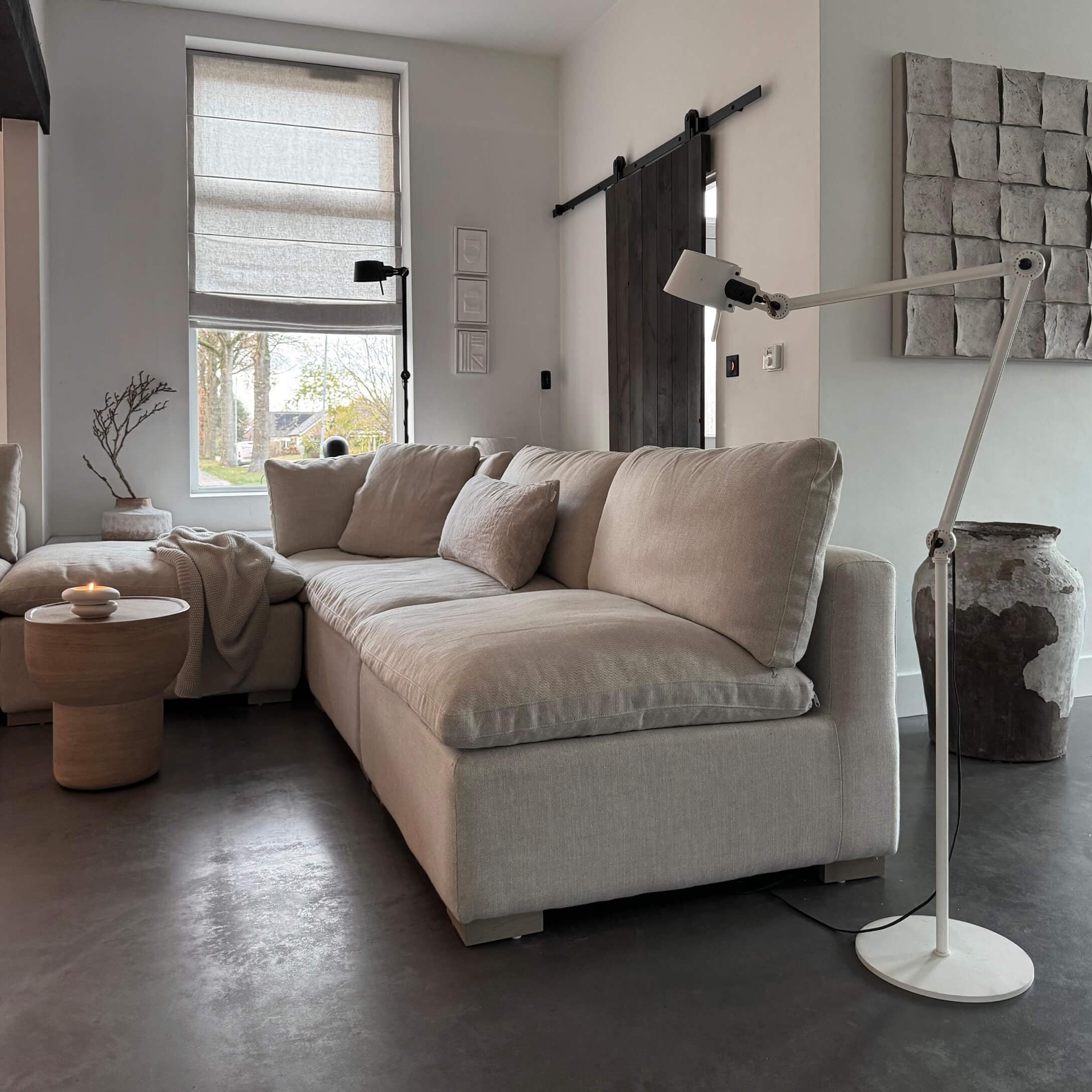 Divano angolare beige in tessuto in soggiorno moderno con lampada da terra e tavolino in legno