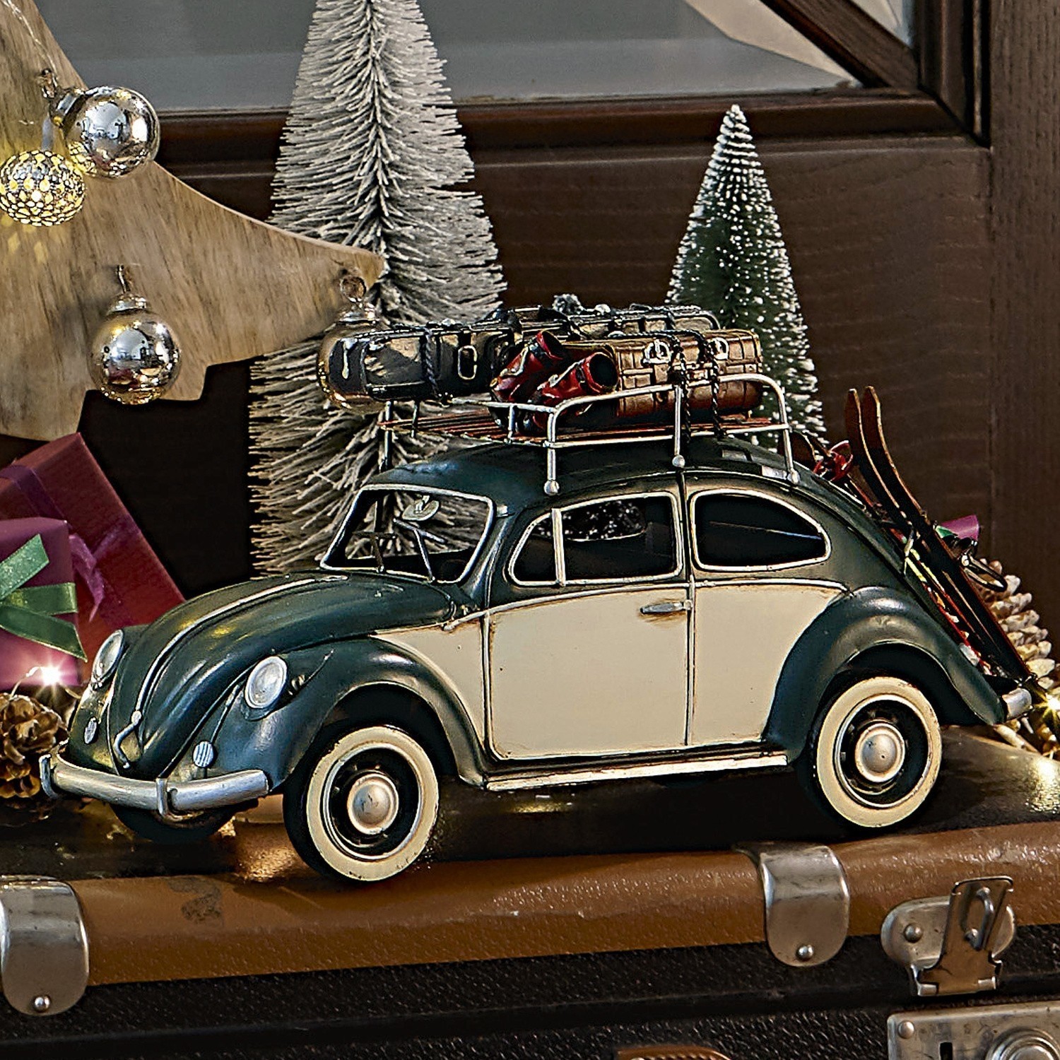 Automobile decorativa Dawlish Modello di auto verde crema con portapacchi in metallo e sci su sfondo di decorazioni natalizie