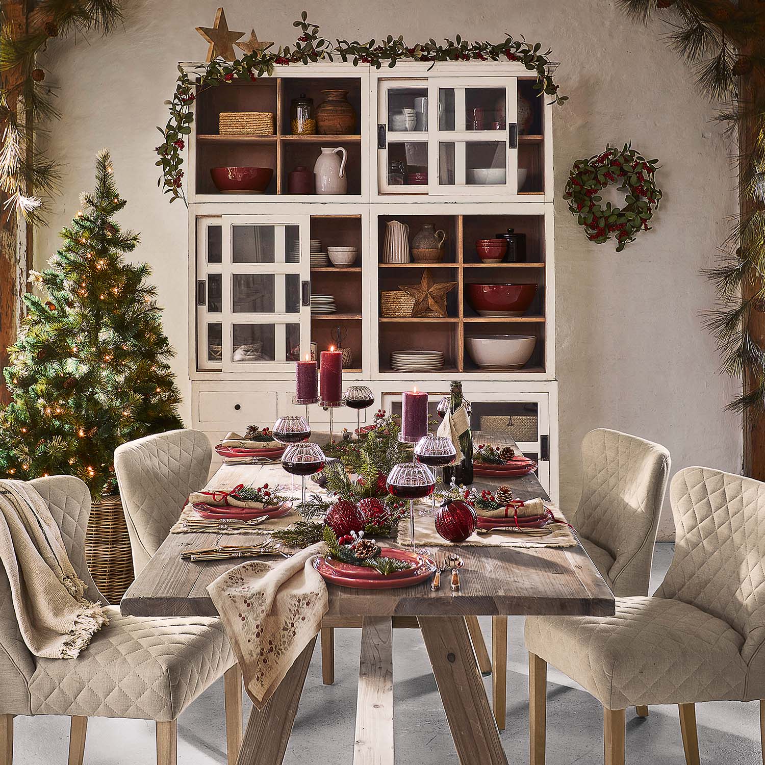 Tavolo rustico in legno con sedie beige trapuntate e decorazioni natalizie in sala da pranzo