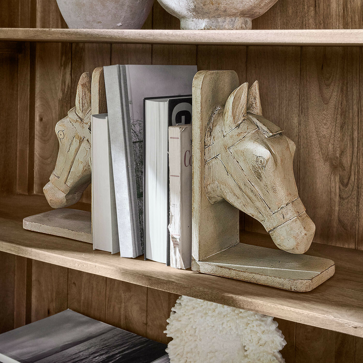 Coppia di fermalibri Caravena Coppia di fermalibri in legno beige a forma di testa di cavallo su mensola con libri