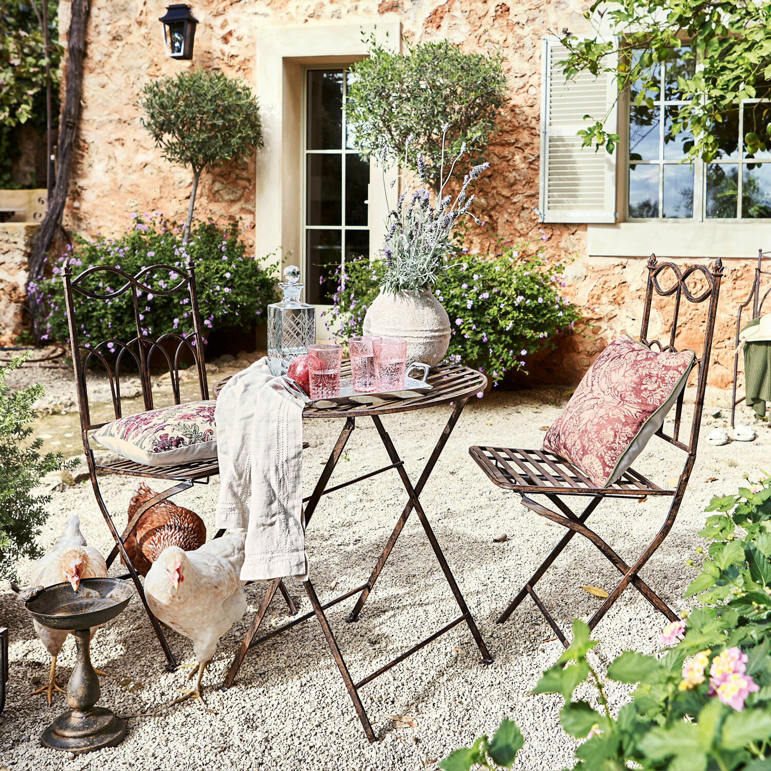 Salottino Fieldbrook Set di mobili da giardino in metallo con tavolo e sedie con cuscini in stile rustico su terrazza ghiaiosa