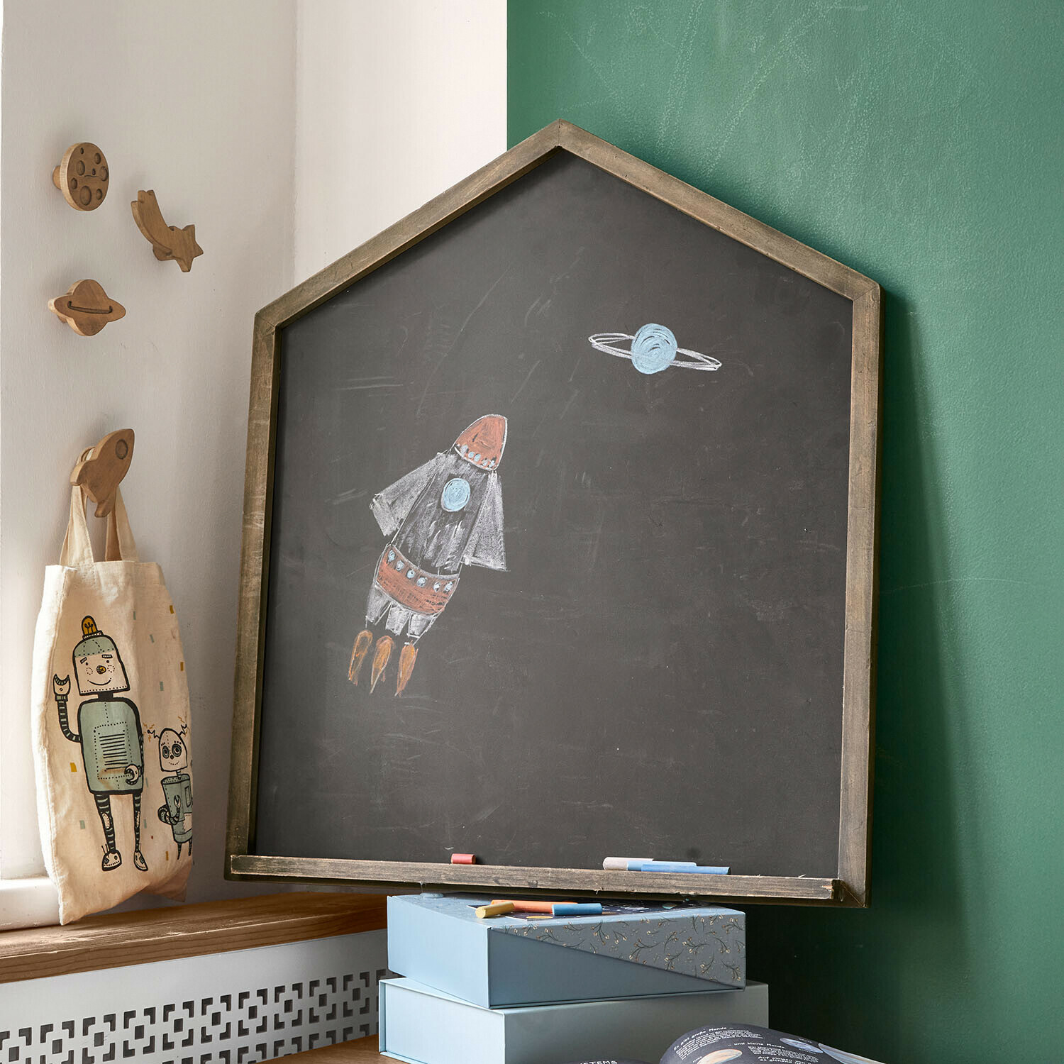 Lavagna Oaklynne Lavagna a forma di casa con cornice in legno e disegno di razzo e pianeta in camera dei bambini