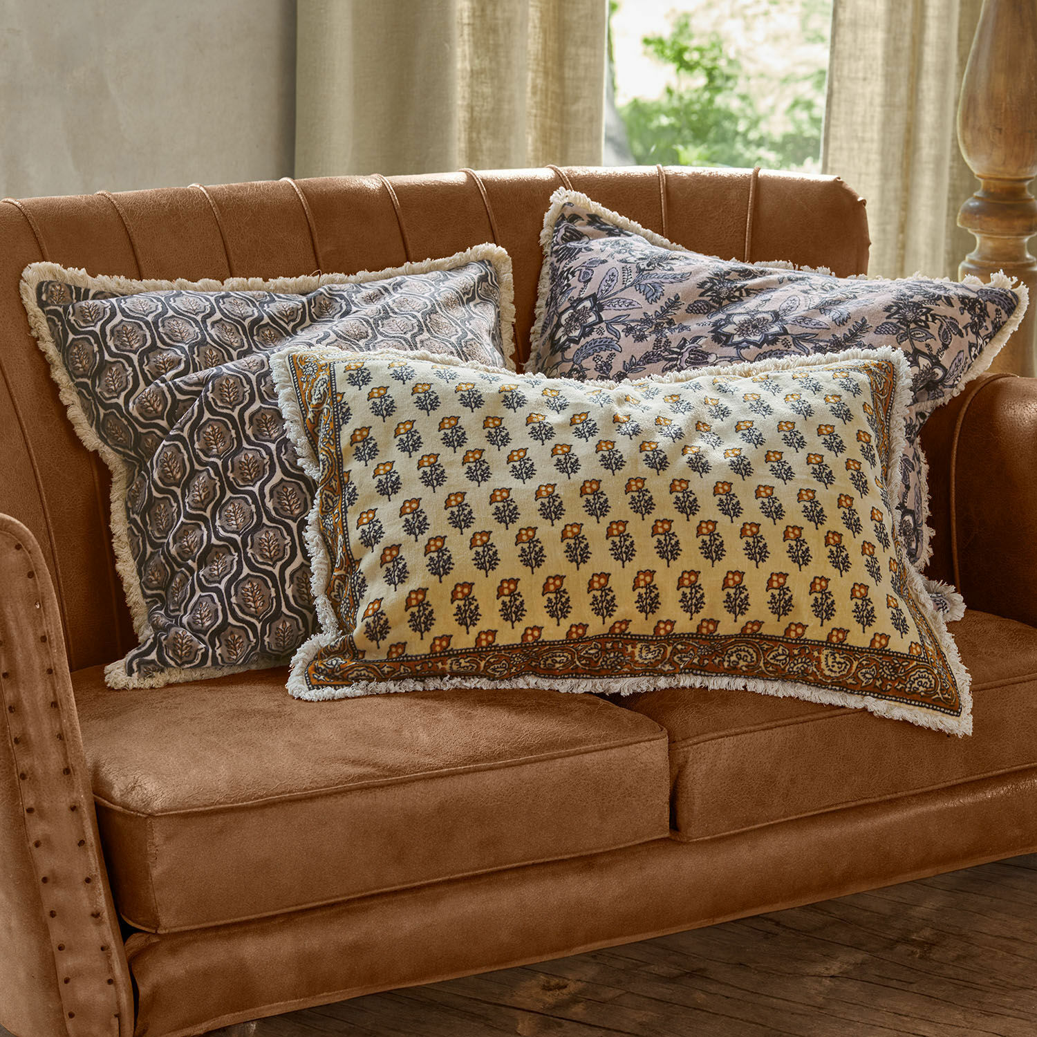Set di 3 copricuscini Zandora Tre cuscini decorativi in cotone con motivo floreale su divano marrone per soggiorno