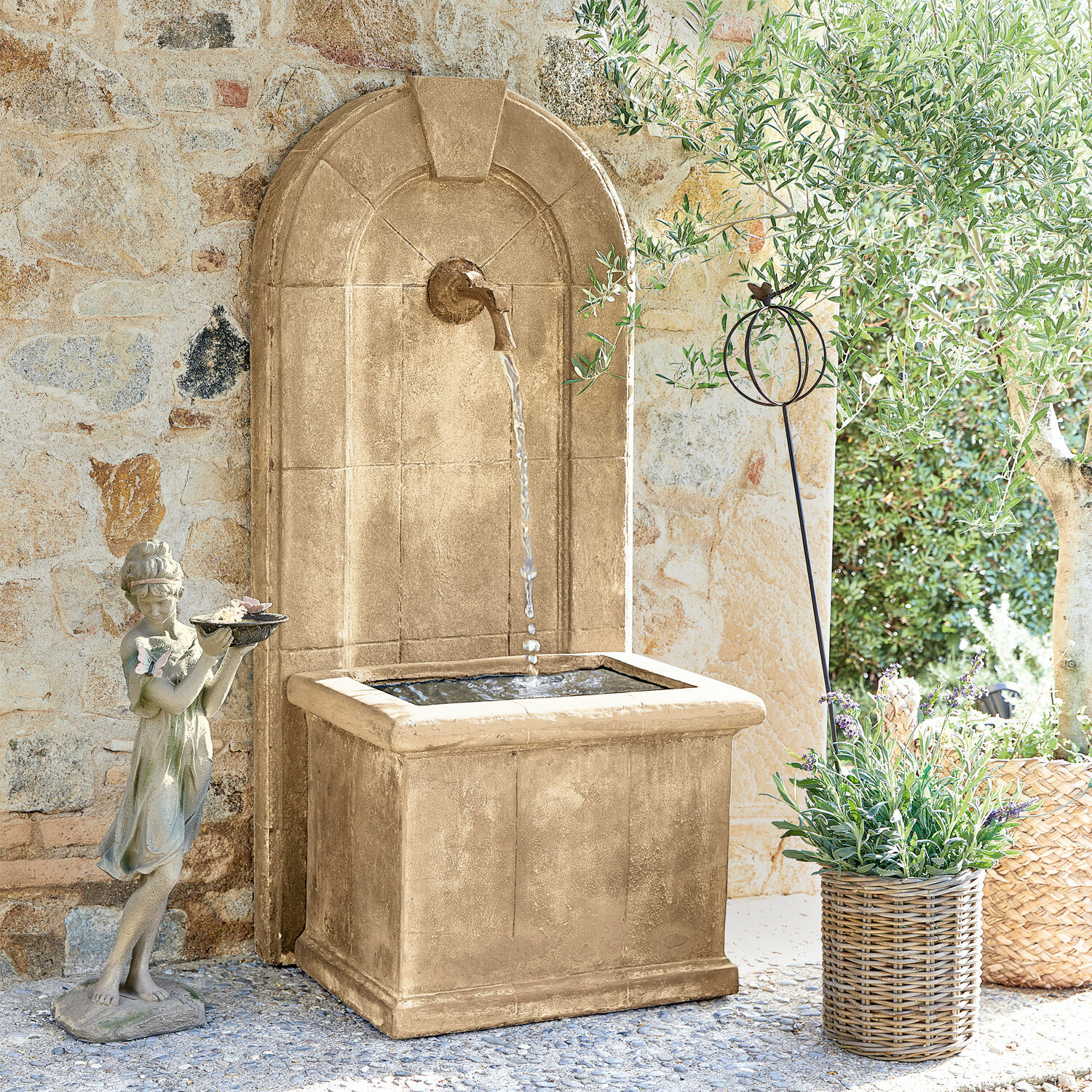 Fontana Ginette Fontana da giardino decorativa in pietra beige con acqua e statua di bambina davanti a muro in pietra