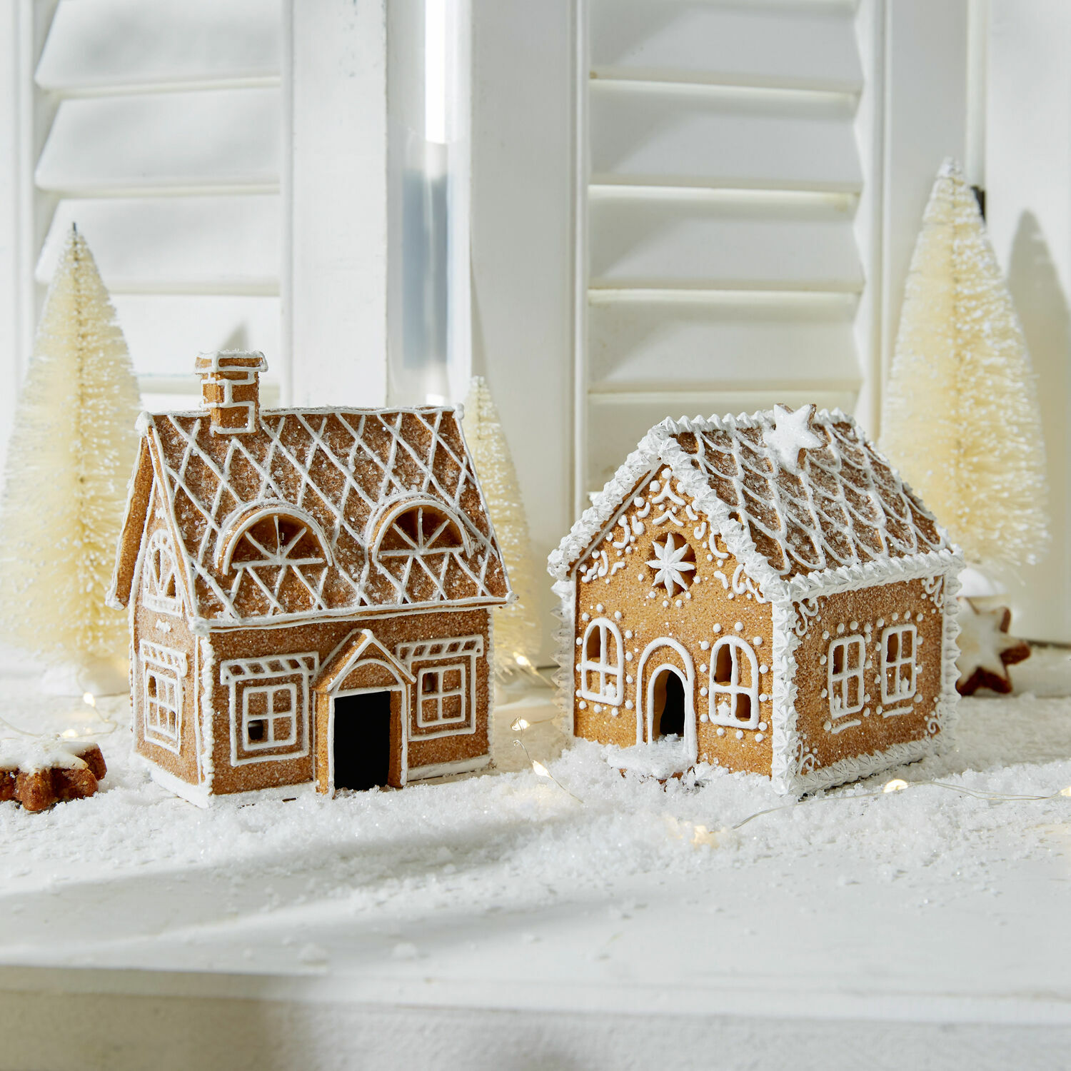 Coppia di casette decorative Tarreau Due casette di pan di zenzero decorate con glassa bianca su tavola natalizia con decorazioni invernali
