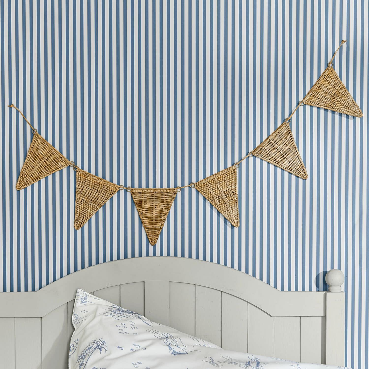Ghirlanda di bandierine Anglemont Ghirlanda decorativa triangolare in vimini su parete a righe blu e bianco in camera da letto