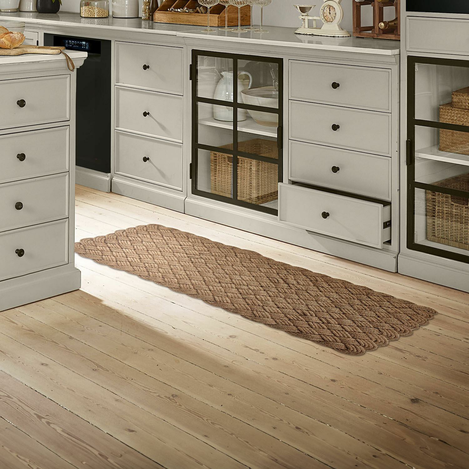 Tappeto Hildas Tappeto marrone intrecciato su pavimento in legno chiaro in cucina con mobili grigi