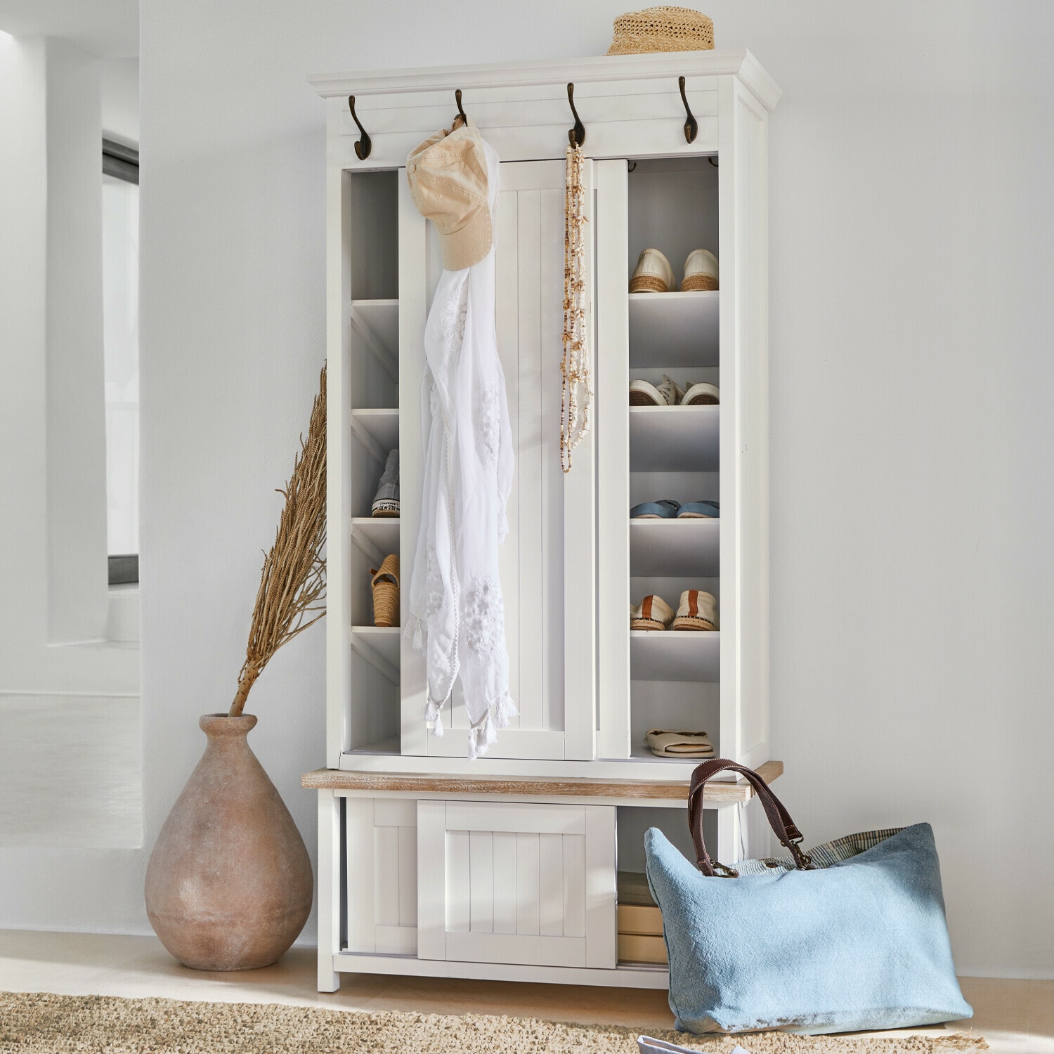 Guardaroba Remerton Armadio porta scarpe in legno bianco con ganci e ripiani, borsa azzurra e cappello di paglia