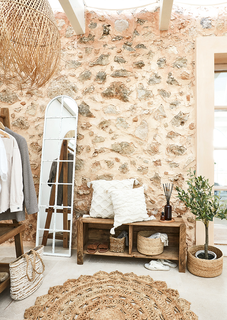 Angolo accogliente con panca in legno, cuscini bianchi e tappeto naturale in juta stile boho