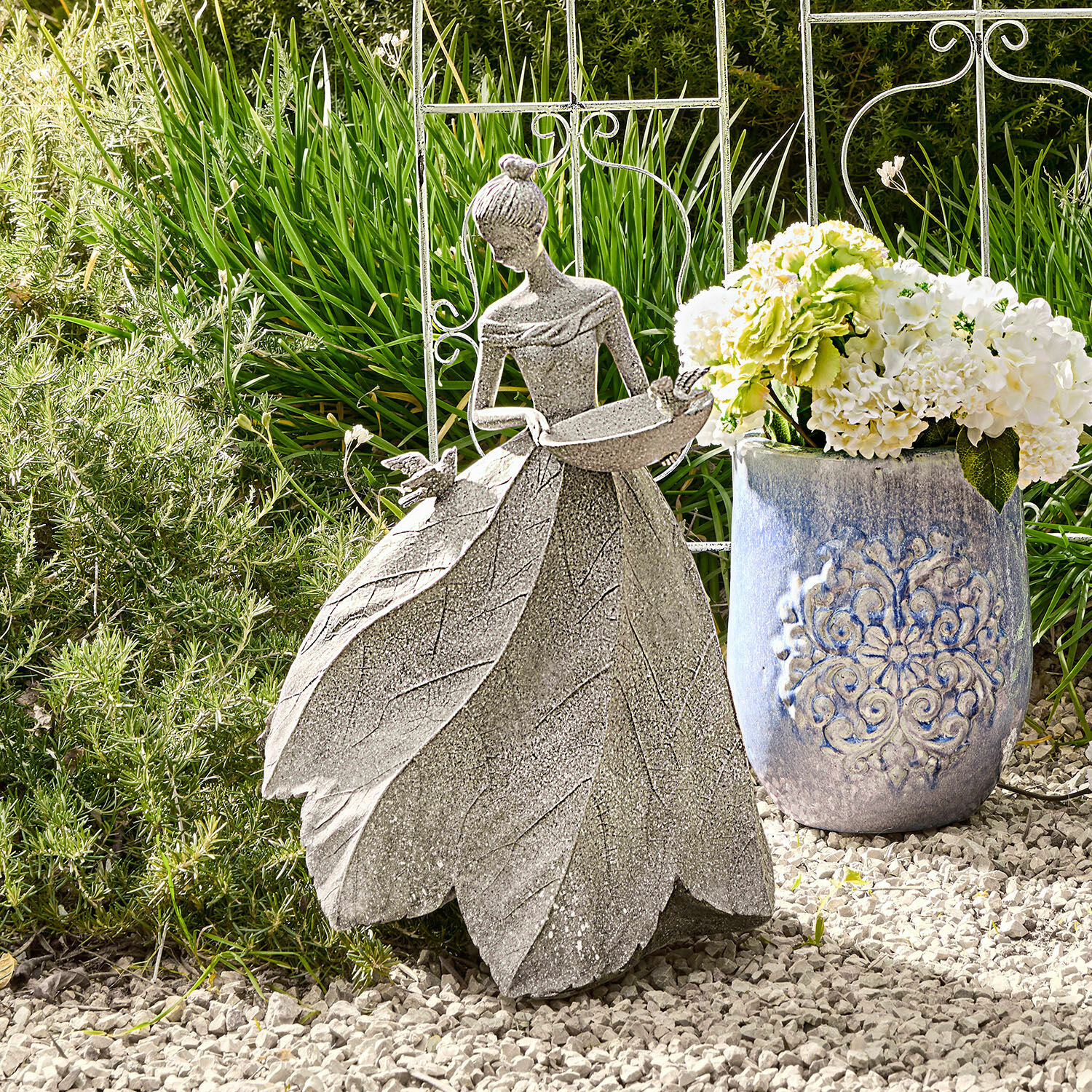 Scultura Sullon Decorazione da giardino in pietra grigia con figura femminile e abito di foglie su ghiaia