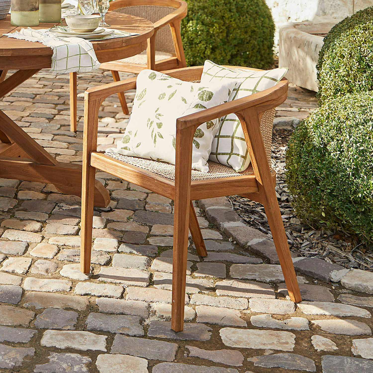 Sedia Wendreau Sedia da giardino in legno con cuscini a motivi verdi su patio lastricato
