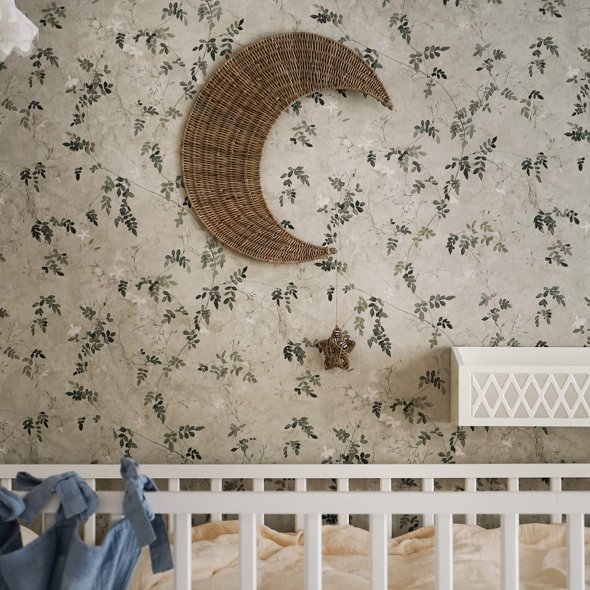 Decorazione da parete luna in vimini con stella appesa su carta da parati floreale in cameretta