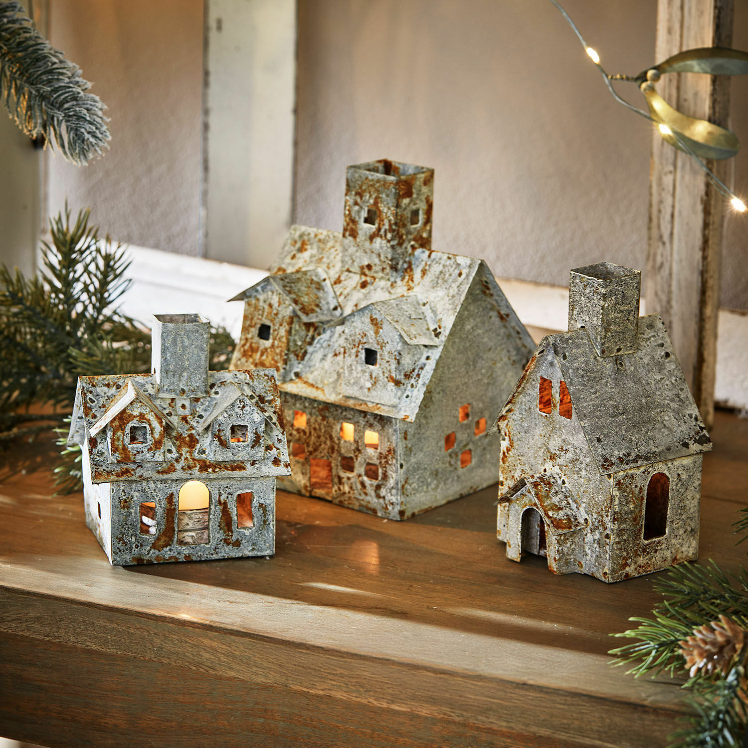 Set di 3 lanterne Granstad Set di tre casette decorative in metallo con effetto ruggine e luce interna su tavolo in legno