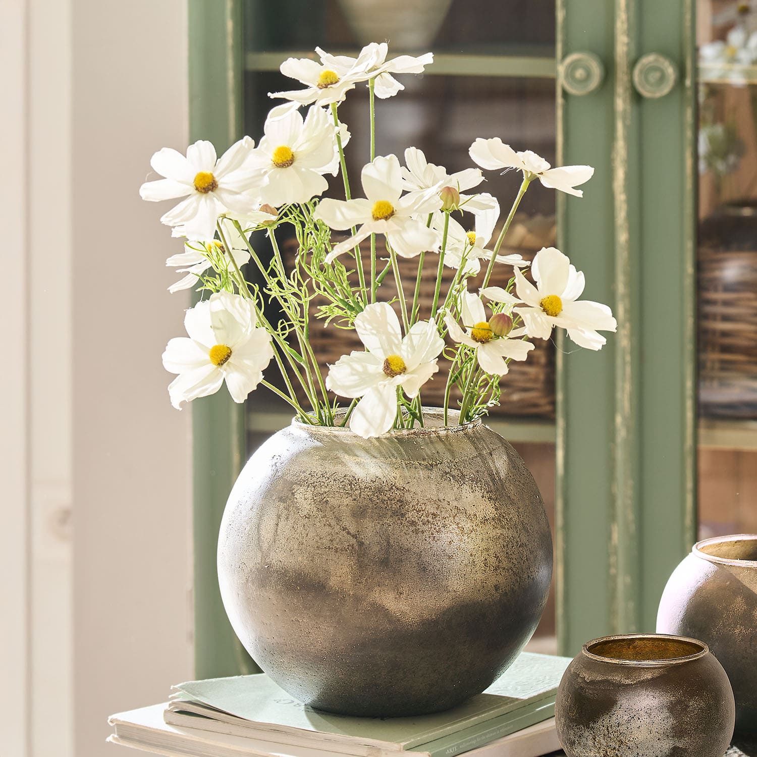 Vaso rotondo in metallo argentato con fiori bianchi su libri, decorazione d'interni elegante