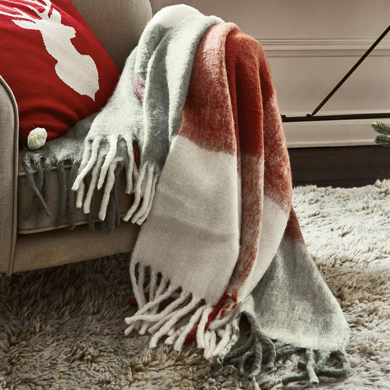 Plaid McGreg Coperta morbida con frange in grigio, bianco e rosso su divano beige, decorazione accogliente