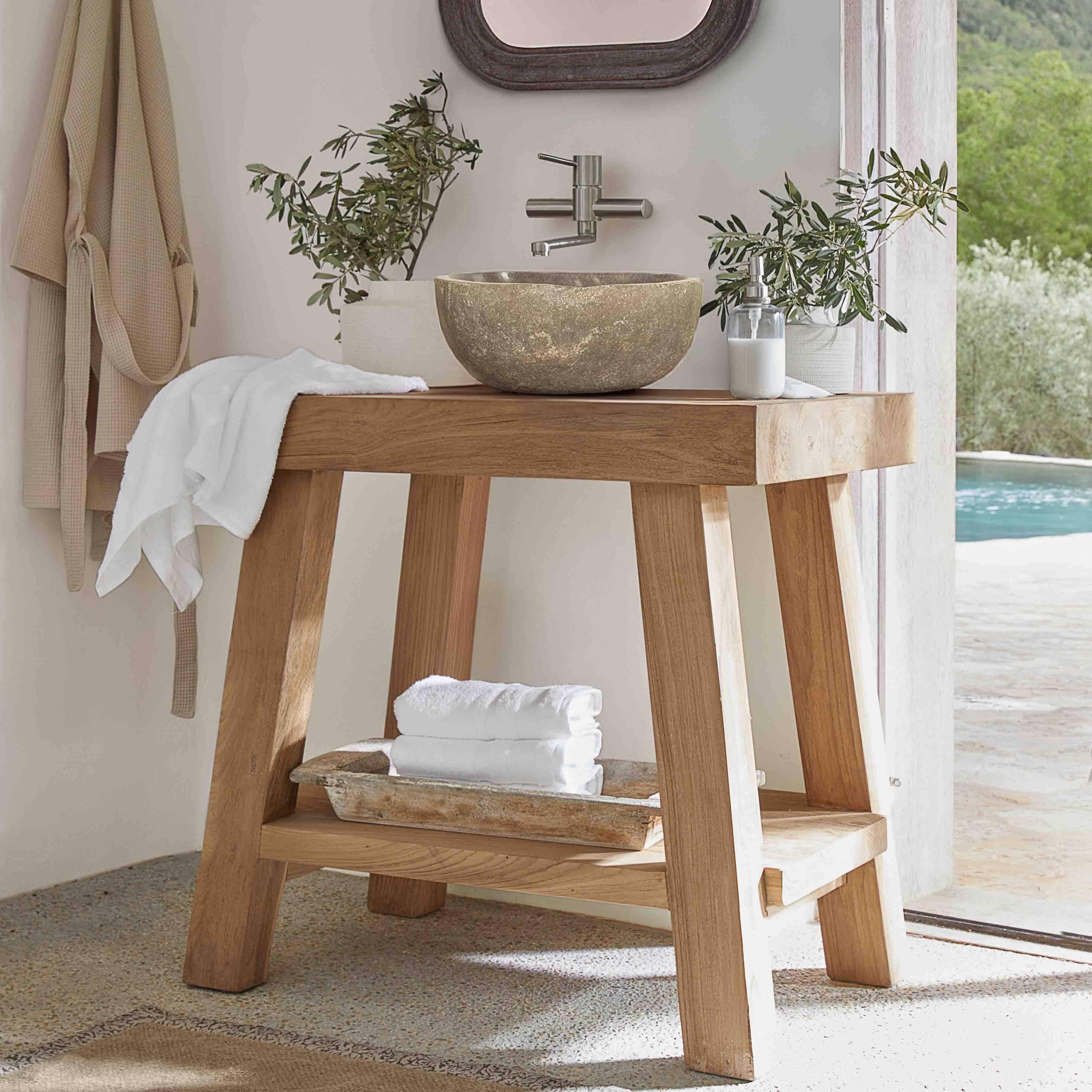 Consolle da bagno in legno con lavabo in pietra e asciugamani bianchi in ambiente luminoso