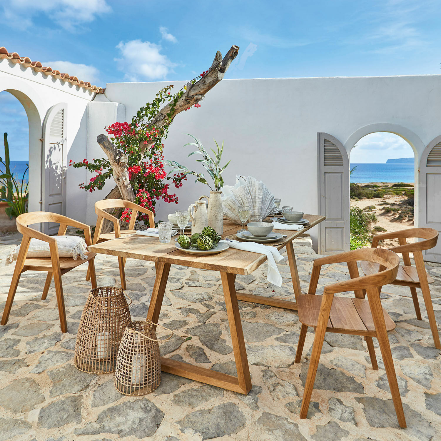 Tavolo Saulny Set di mobili da giardino in teak con sedie e tavolo su patio in pietra con vista mare