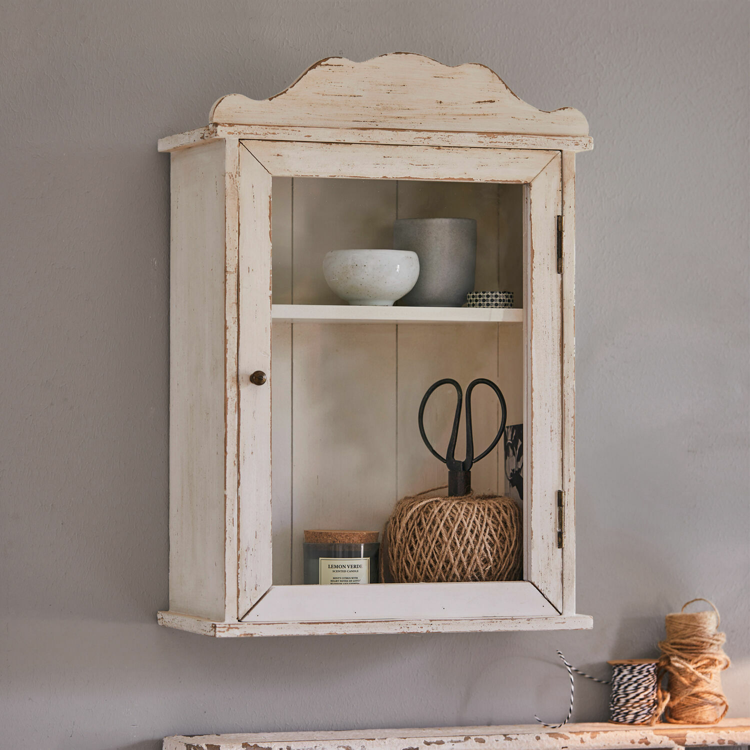 Vetrinetta pensile Sandrine Mobiletto da parete in legno bianco in stile vintage con porta in vetro e oggetti decorativi all'interno
